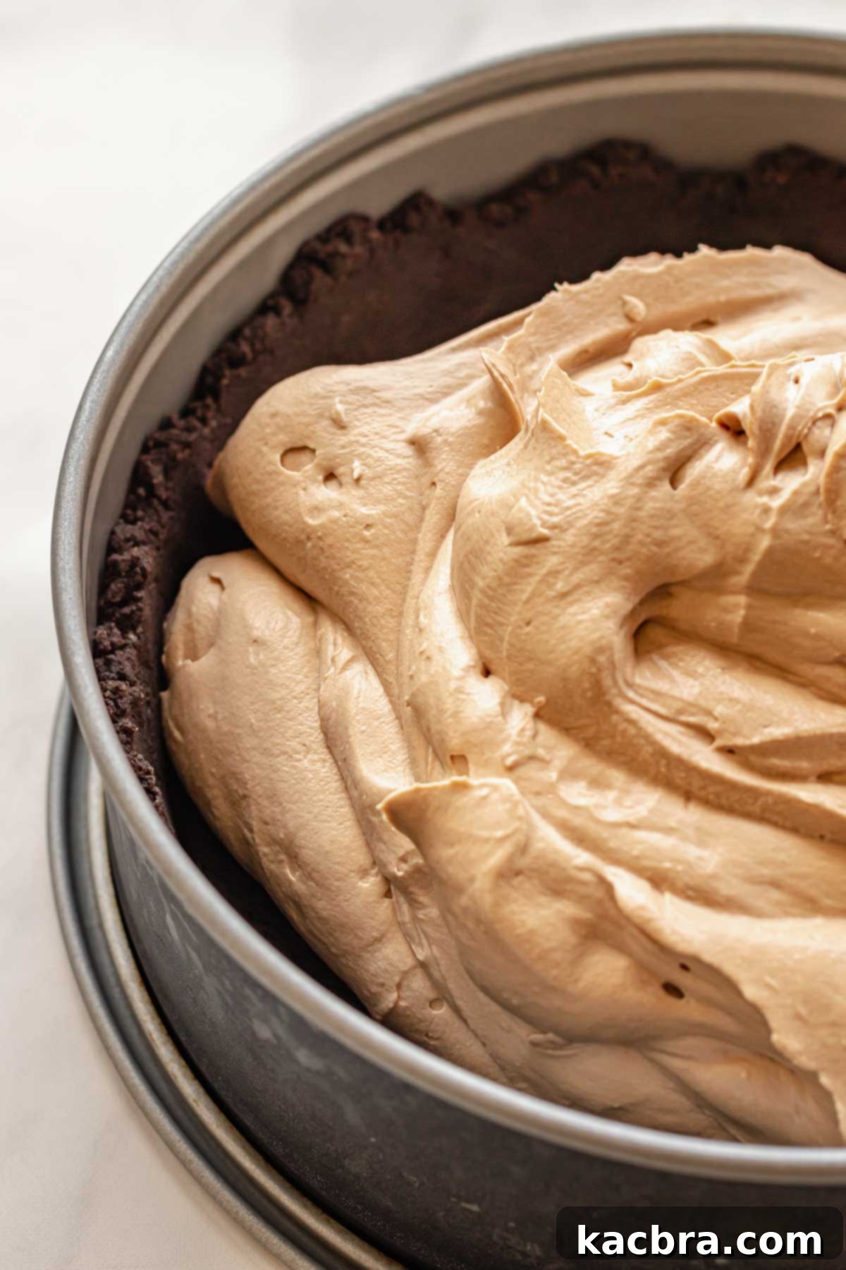 The smooth and creamy Baileys cheesecake batter poured evenly into the frozen Oreo crumb crust in a springform pan.