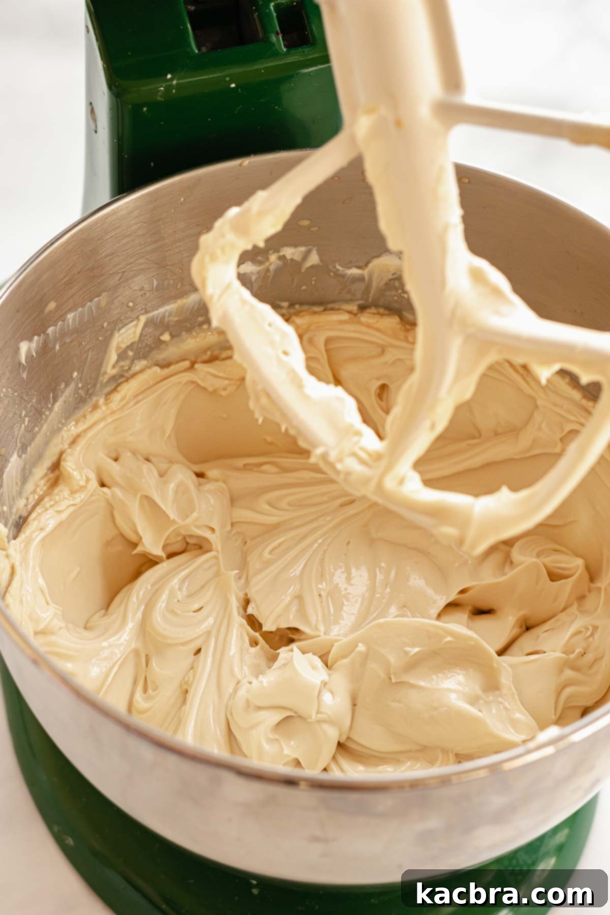 The Baileys-infused cheesecake batter, now light and fluffy, filling the bowl of a stand mixer, demonstrating its smooth and airy consistency.