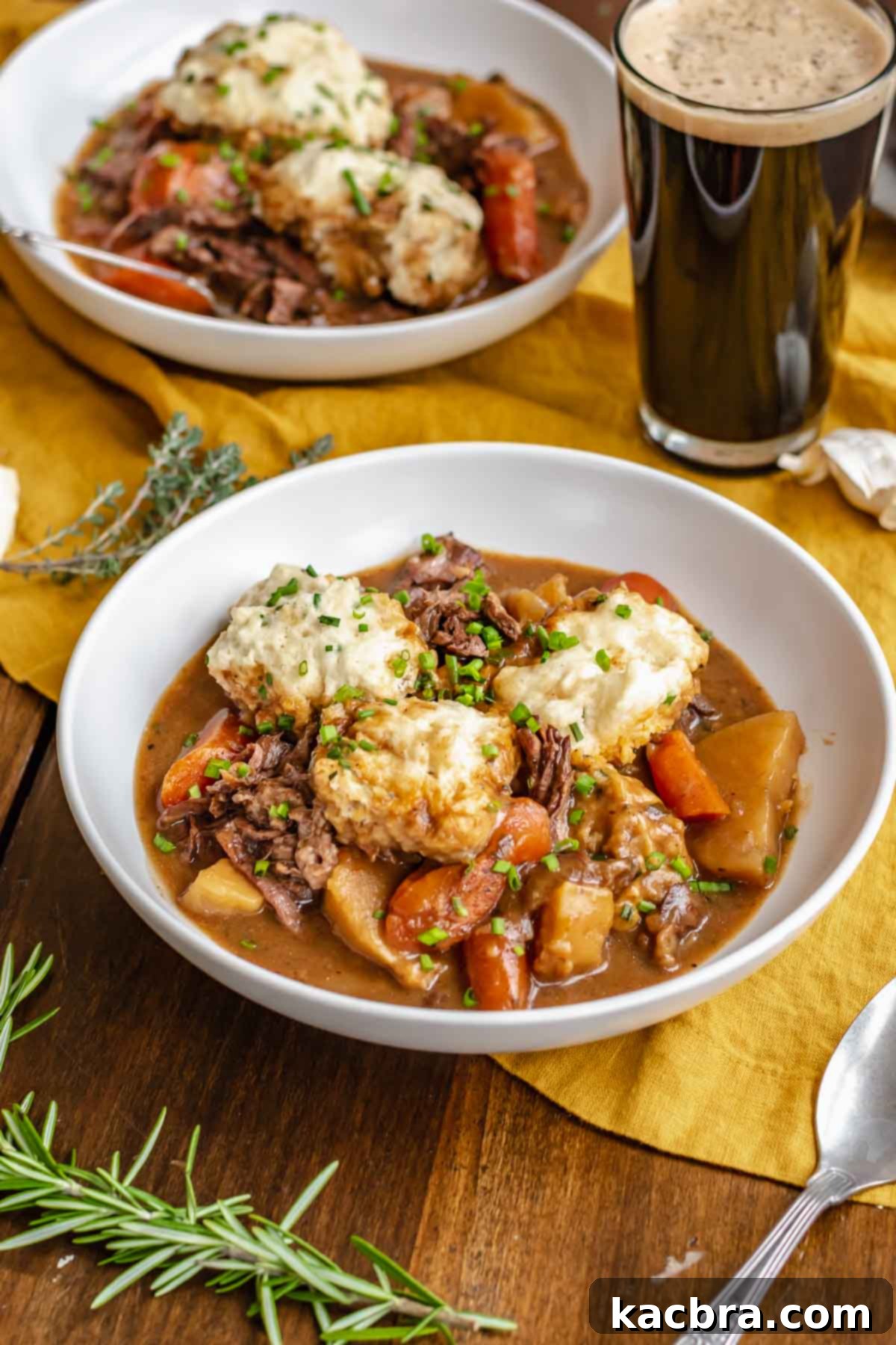 Bowls of beef stew with dumplings and a glass of Guinness.