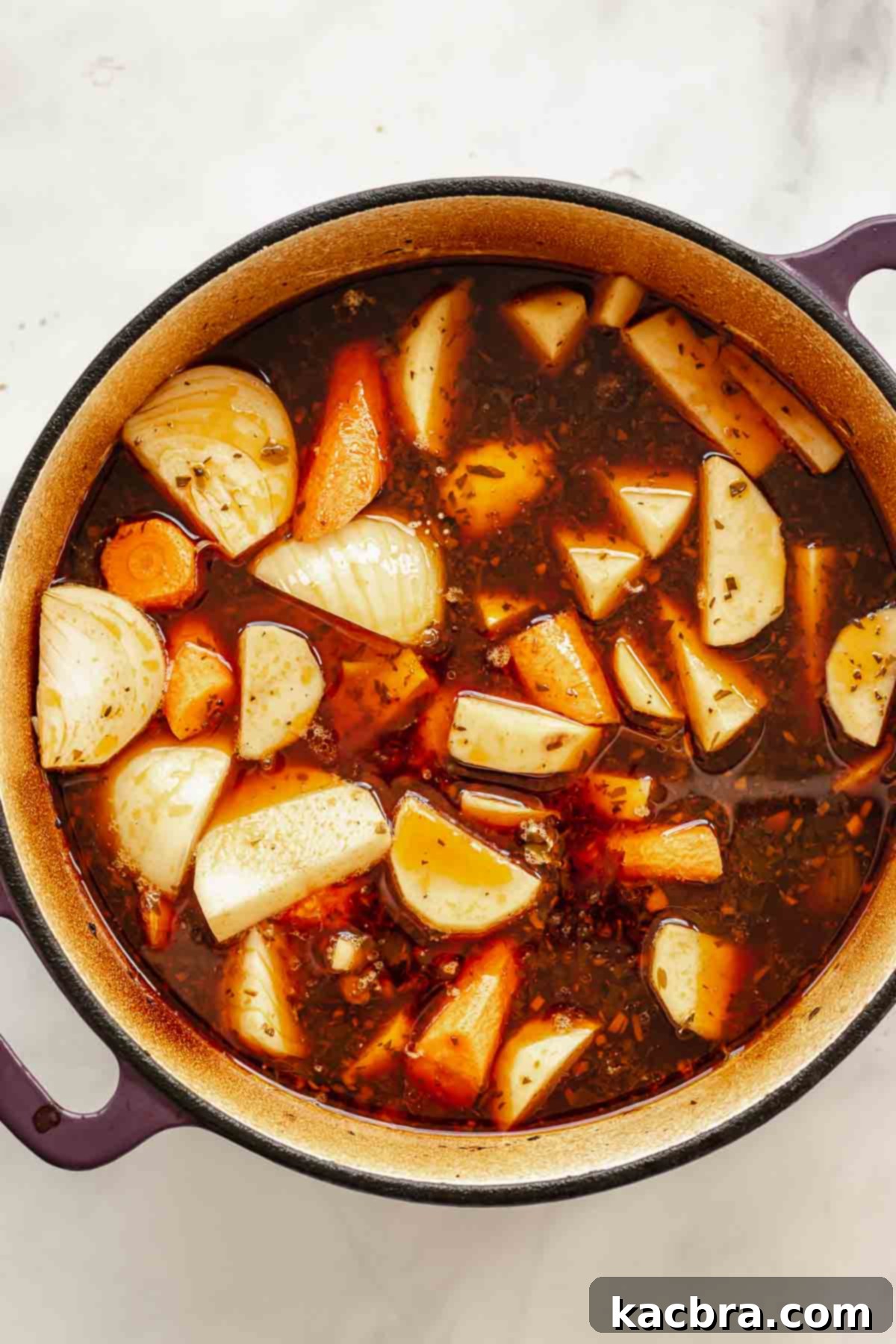 Vegetables added to beef stock in a pot.