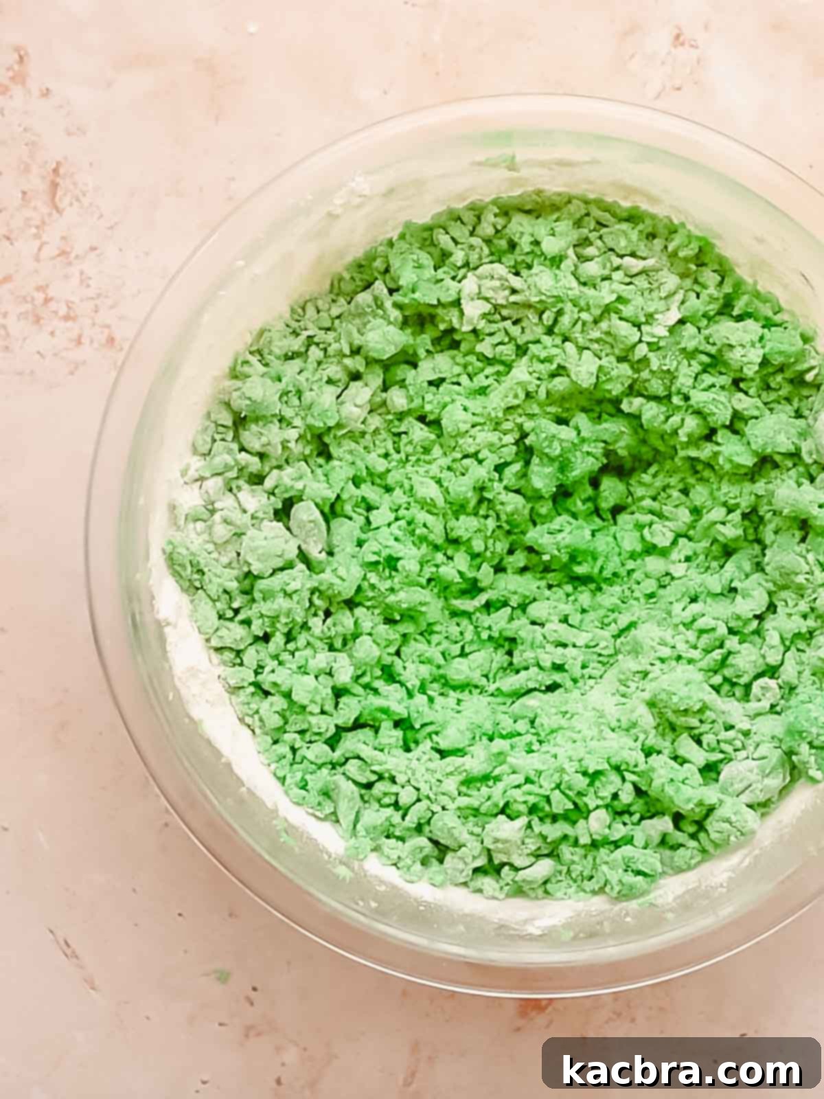 Green cookie dough in a bowl with flour being mixed in.