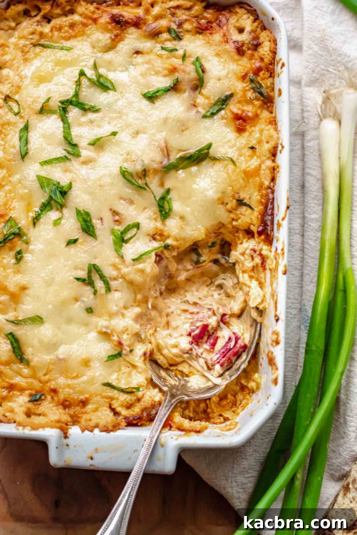 A spoon rests in a casserole dish with dip on it.
