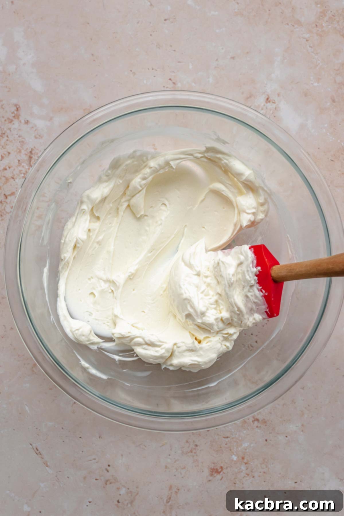 Cream cheese softened in a bowl with a spatula in it.