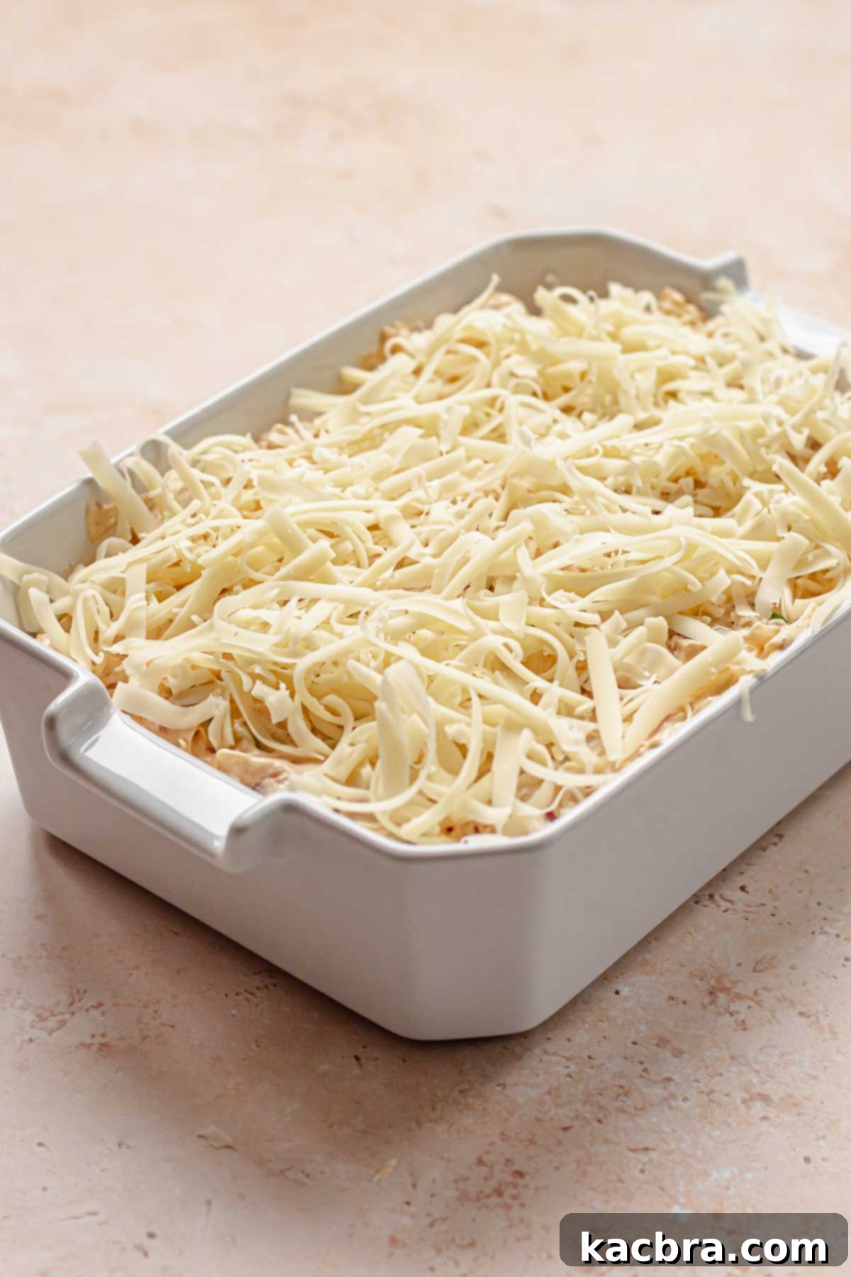 Pre-baked dip in a dish with shredded cheese on top.