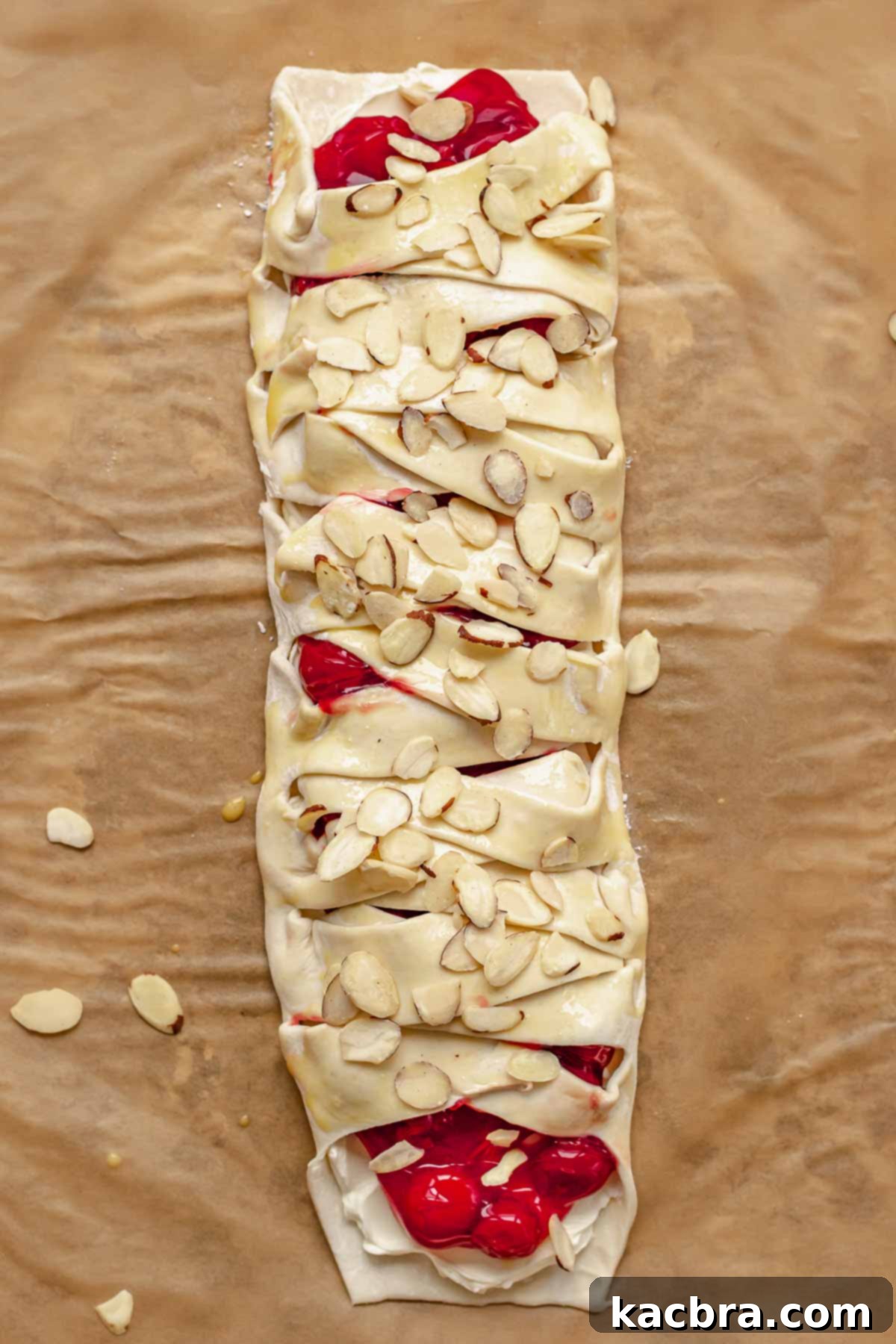 Sliced almonds sprinkled on top of the pre-baked danish, glistening with egg wash.