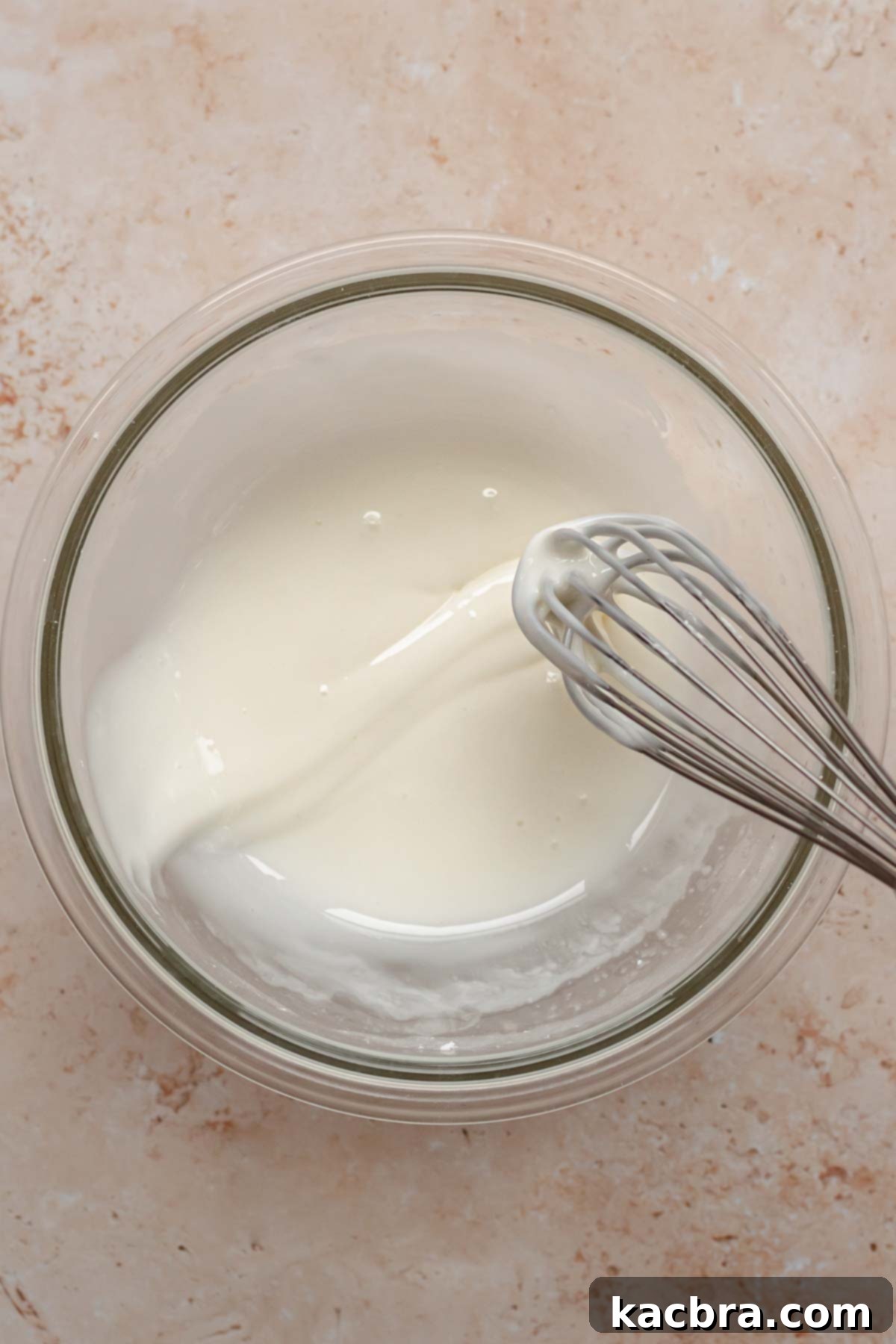 Powdered sugar, milk, and almond extract in a bowl, being whisked for the glaze.