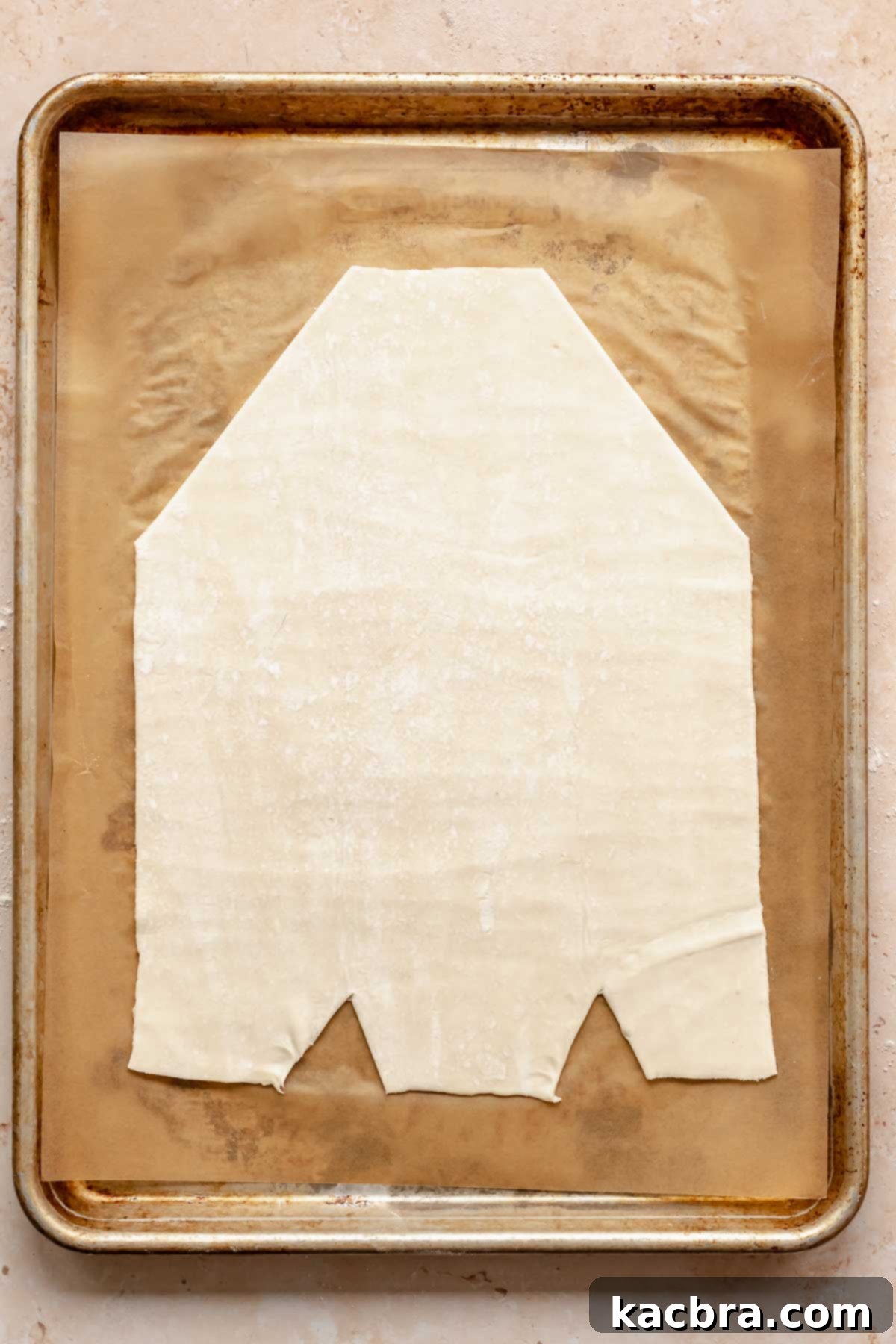 A prepared danish base with cut corners and strips on a cookie sheet.