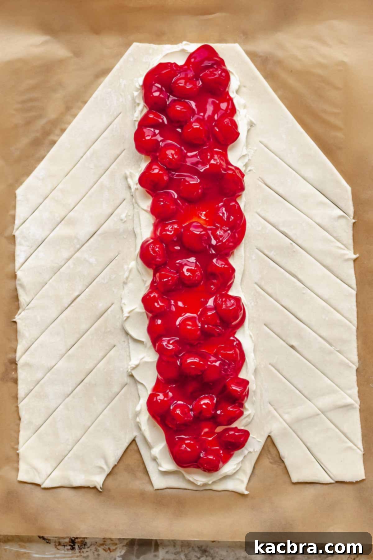 Flaky Cherry Cream Cheese Pastry 8 The sides of the puff pastry are cut into diagonal strips, almost reaching the central filling.