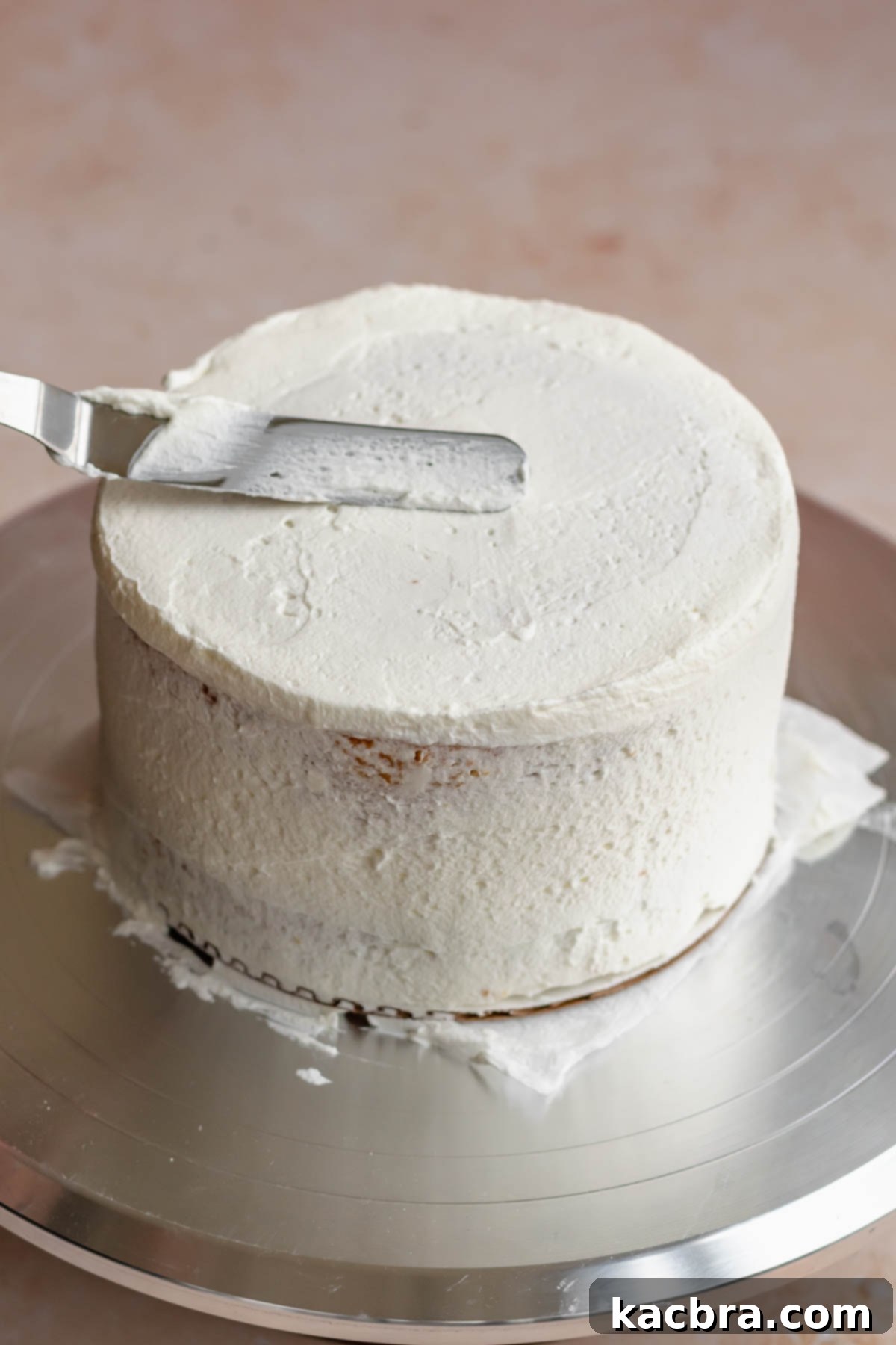 Crimson Kissed Almond Delight 16 An offset spatula smoothing a thin layer of frosting (crumb coat) over the entire cake.