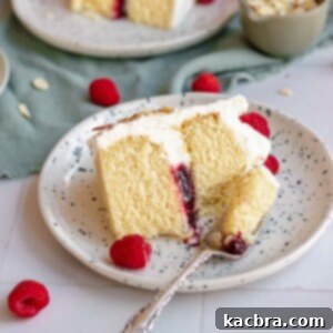 Crimson Kissed Almond Delight 20 Almond raspberry cake slice on a plate. A fork remove a piece.