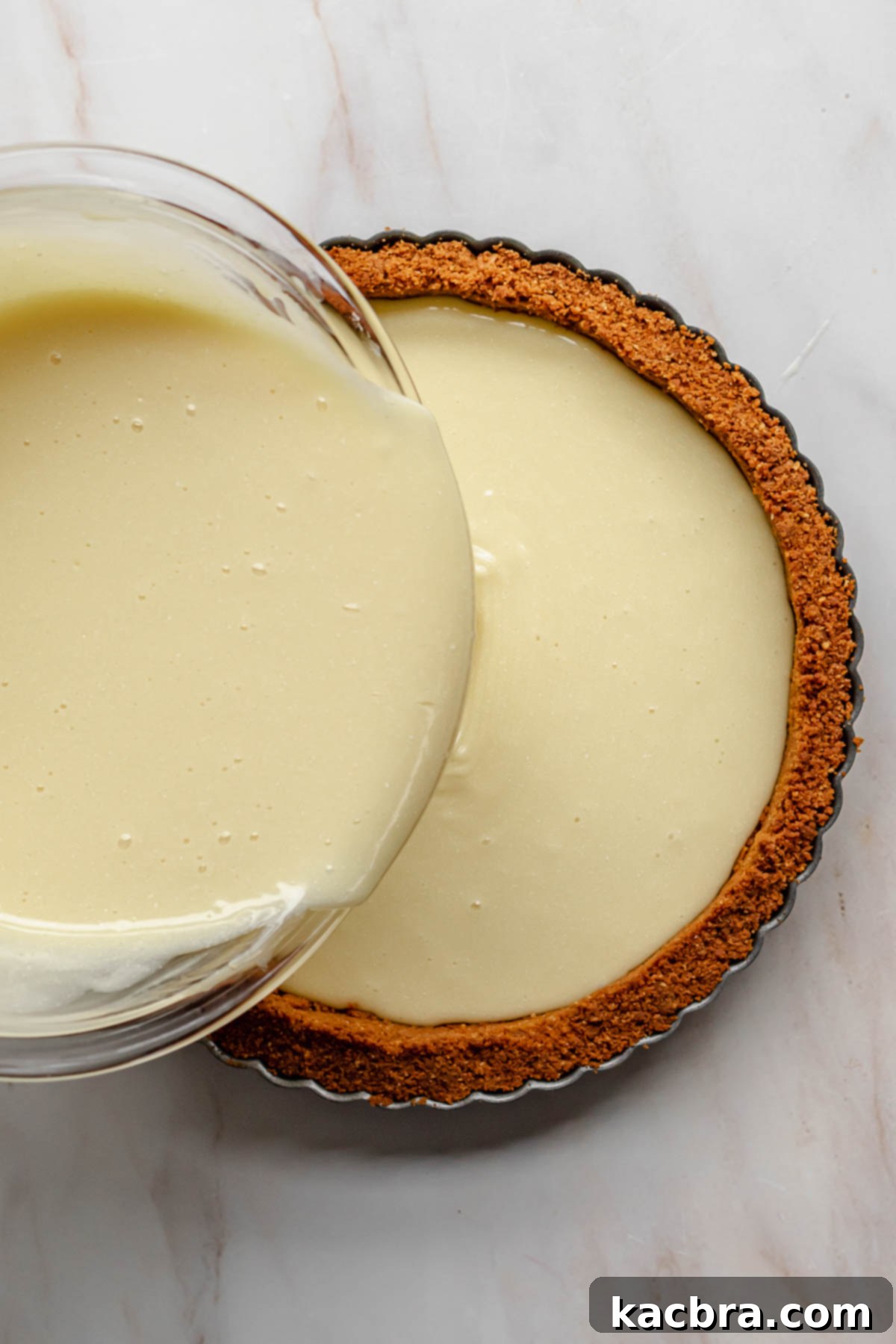 Pouring the smooth white chocolate ganache into the pre-baked and cooled Biscoff cookie tart shell.