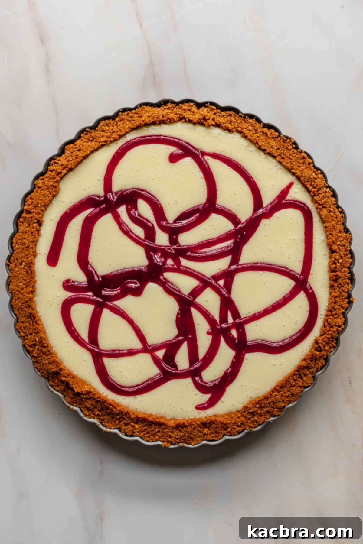Cranberry puree being piped in decorative swirls onto the top of the white chocolate ganache in the tart shell.