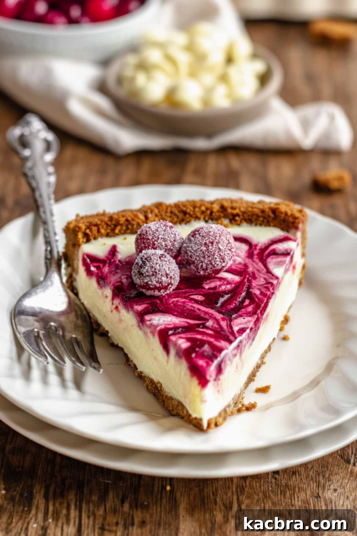A slice of the decadent white chocolate cranberry tart on a white plate, with a silver fork beside it, ready to be enjoyed.