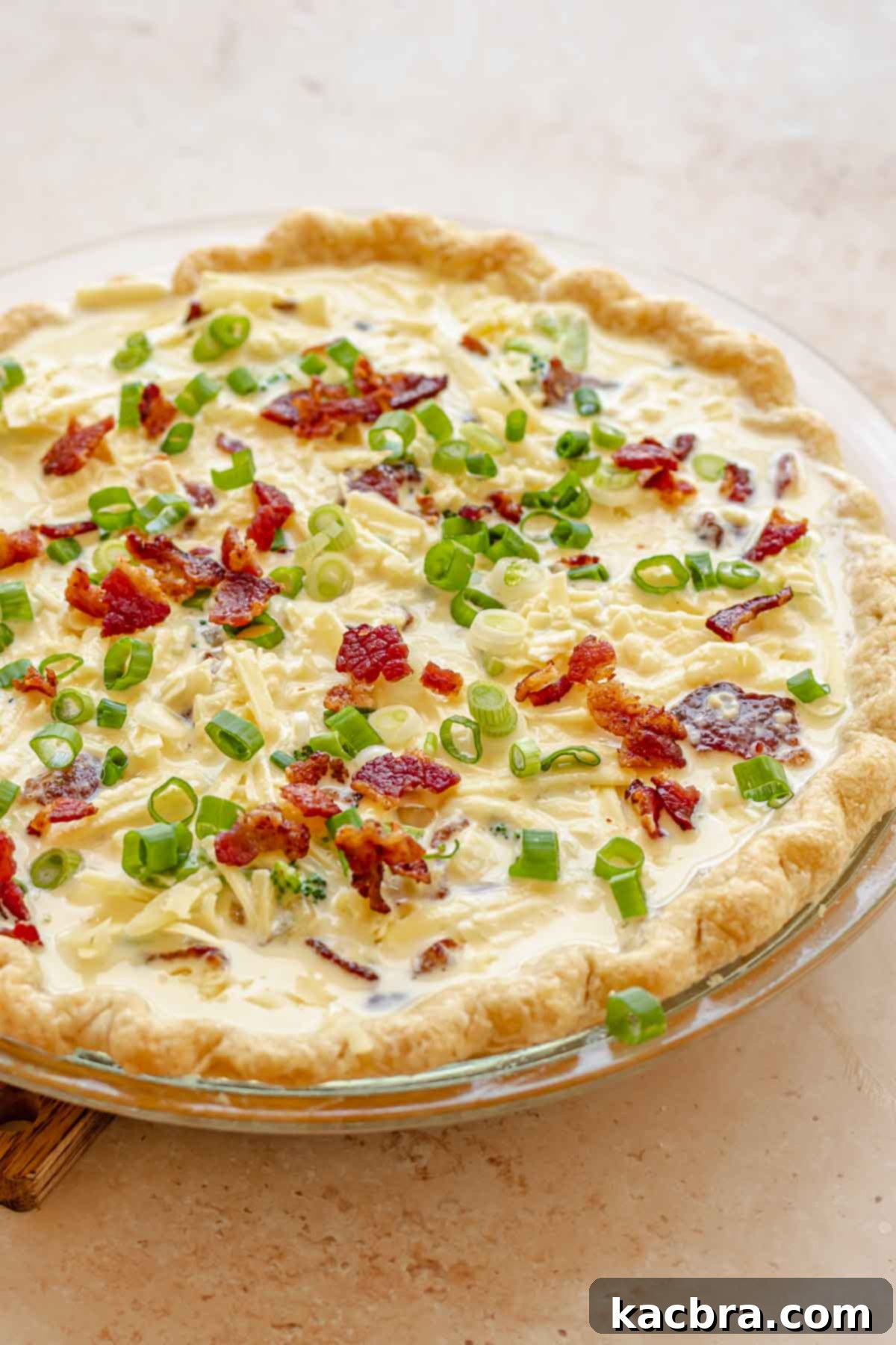 Pre-baked quiche topped with freshly chopped scallions, ready to be served.