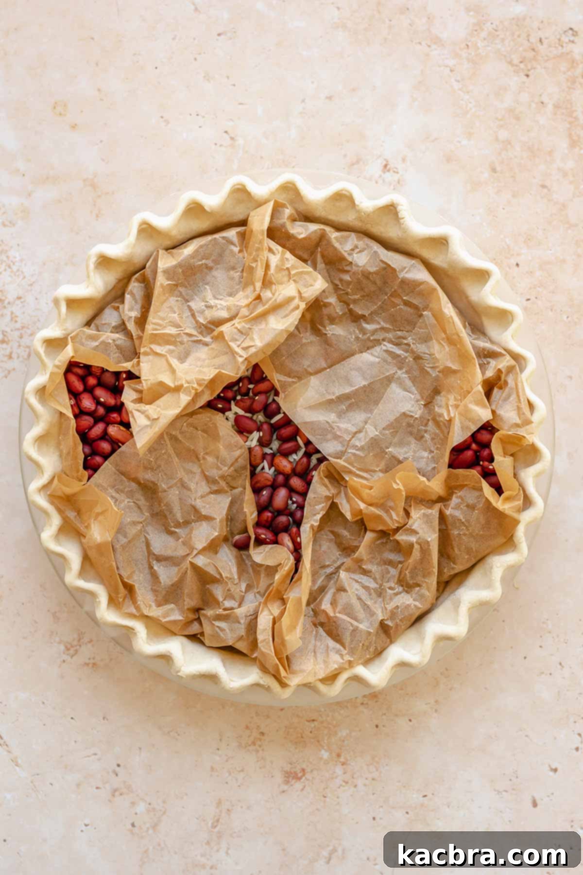 Parchment paper and pie weights in a raw pie crust, ready for par-baking.
