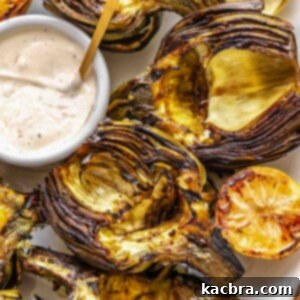 Grilled artichokes on a platter with dipping sauce.