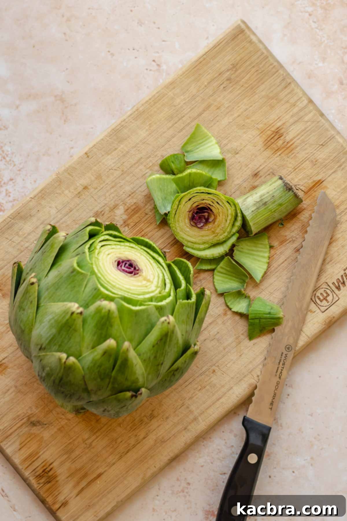 Artichoke with the top removed on a cutting board.