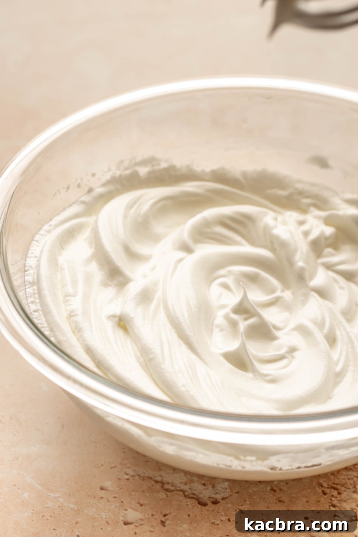 Whipped egg whites in a bowl, showing stiff peaks.