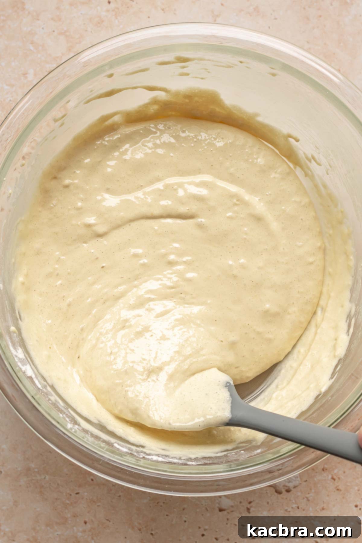 A spatula gently stirs dry ingredients into sponge cake batter.