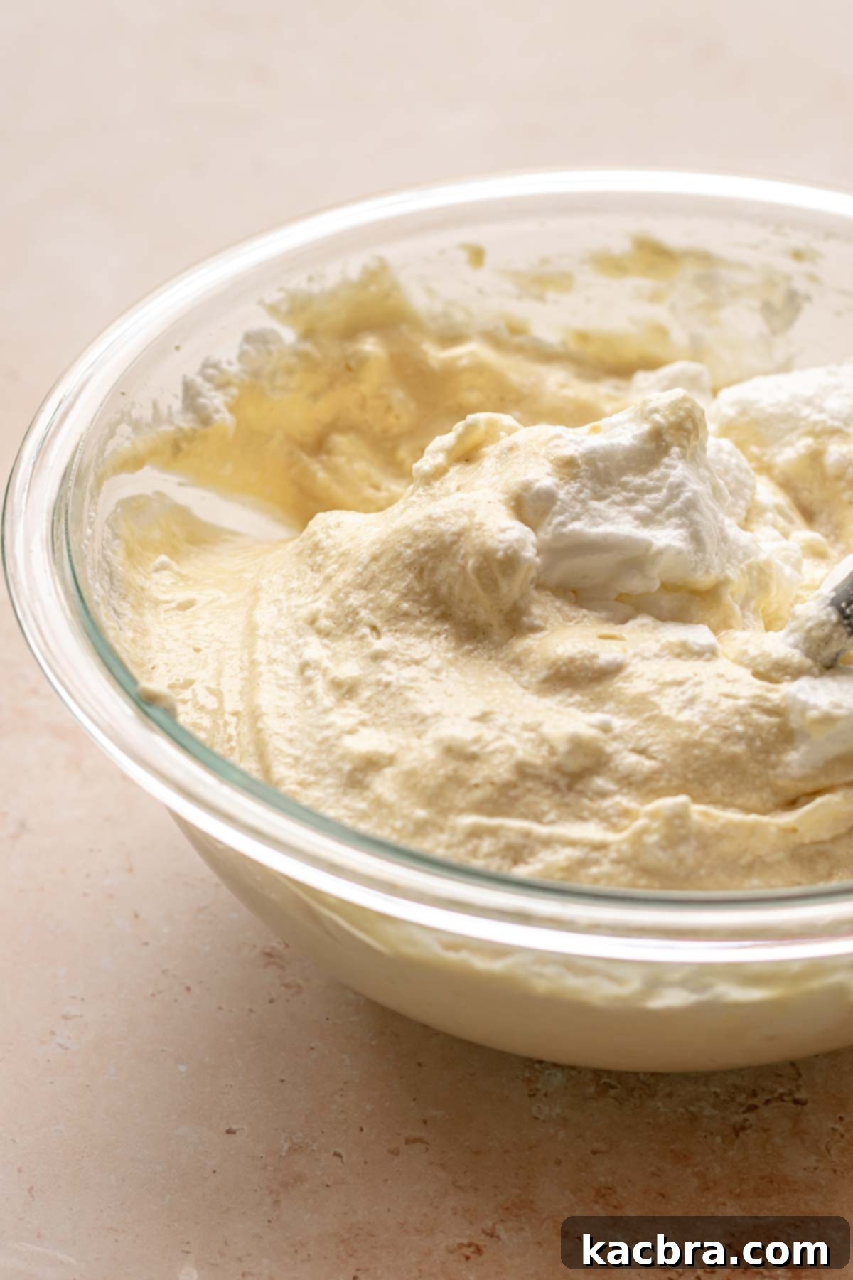 A spatula delicately folds whipped egg whites into the cake batter.