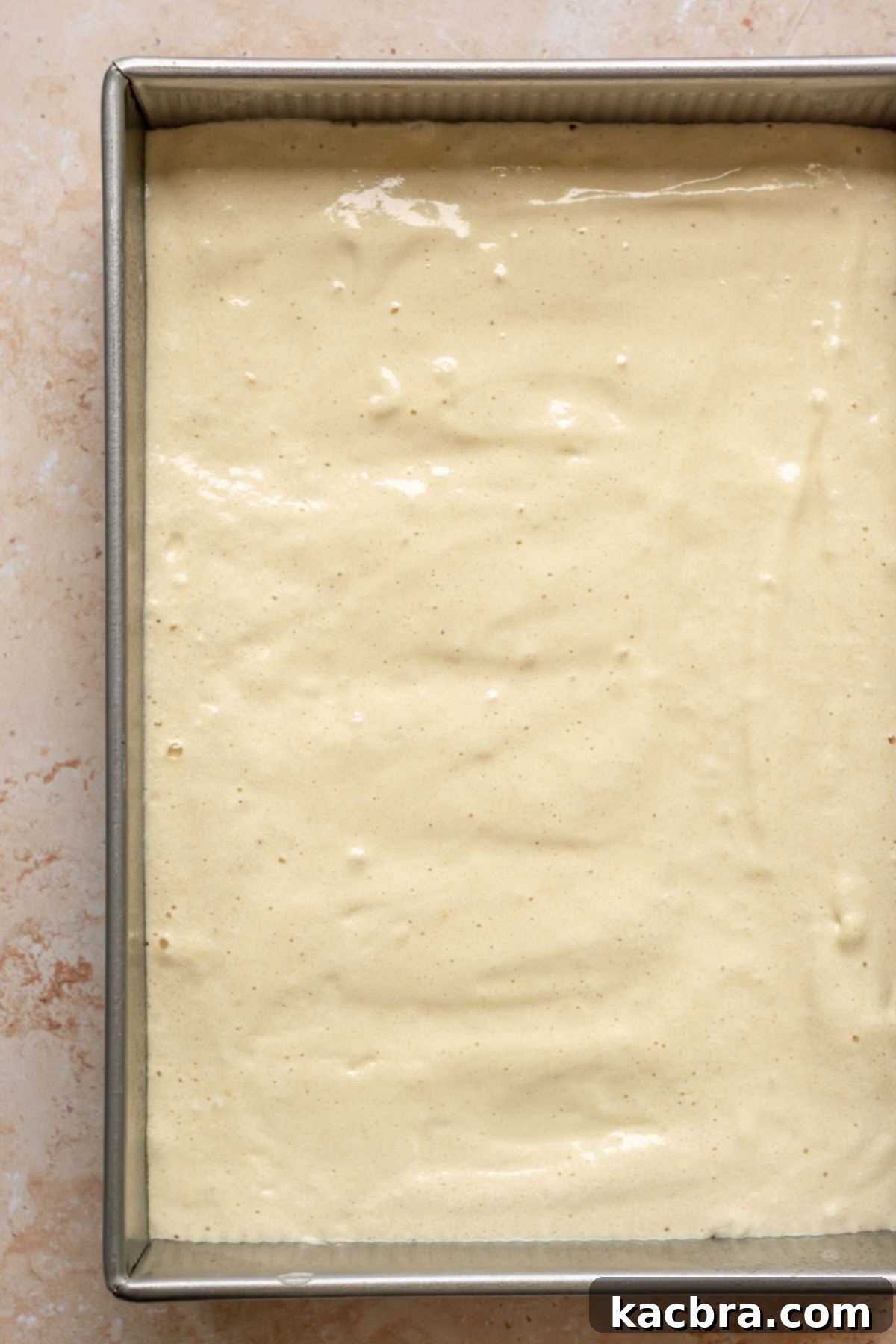 Sponge cake batter evenly spread in a 9x13 inch baking pan.