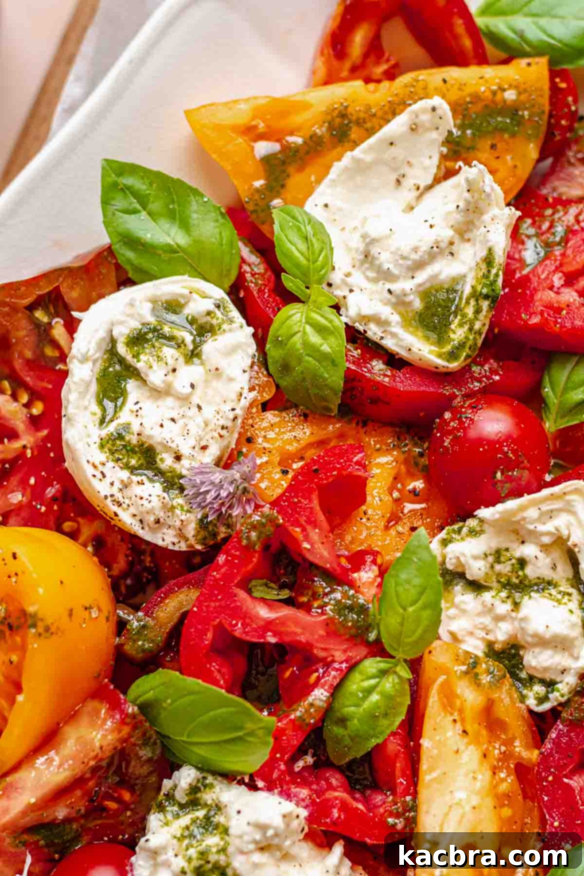 Fresh Burrata Caprese Drizzled with Aromatic Garlic Basil Oil 2 Caprese salad with burrata on a platter.