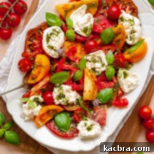 Fresh Burrata Caprese Drizzled with Aromatic Garlic Basil Oil 12 Caprese salad with burrata on a platter.