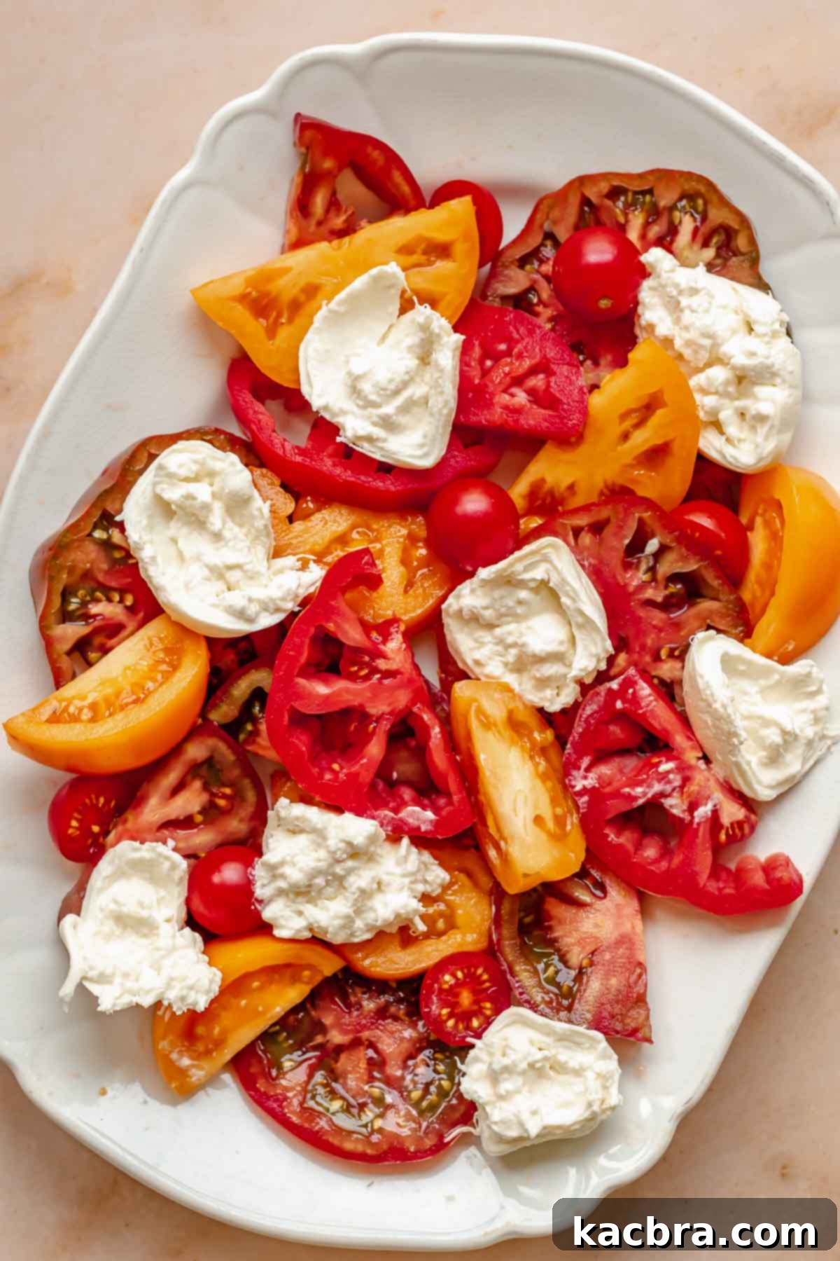 Fresh Burrata Caprese Drizzled with Aromatic Garlic Basil Oil 7 Tomatoes and torn burrata on a platter.