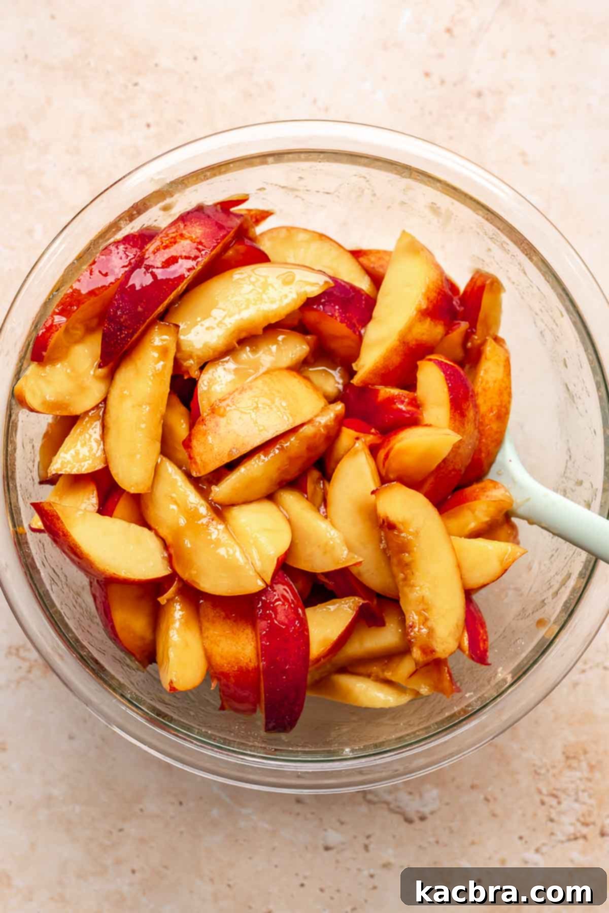Golden Skillet Peach Cobbler 5 Sliced peaches in a bowl with a spatula.