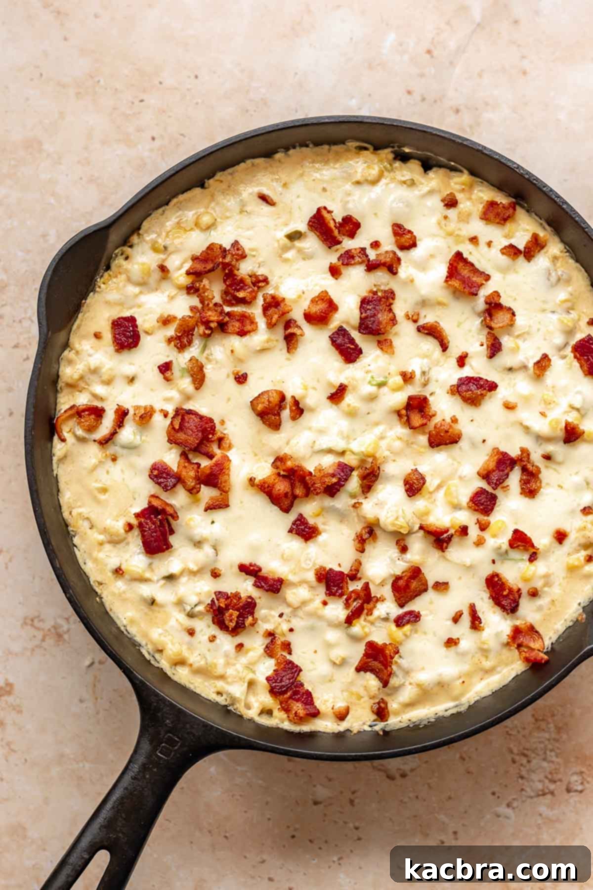 Kickin' Jalapeño Corn Dip 11 Hot corn dip in a skillet with melted cheese and cooked bacon pieces on the top.
