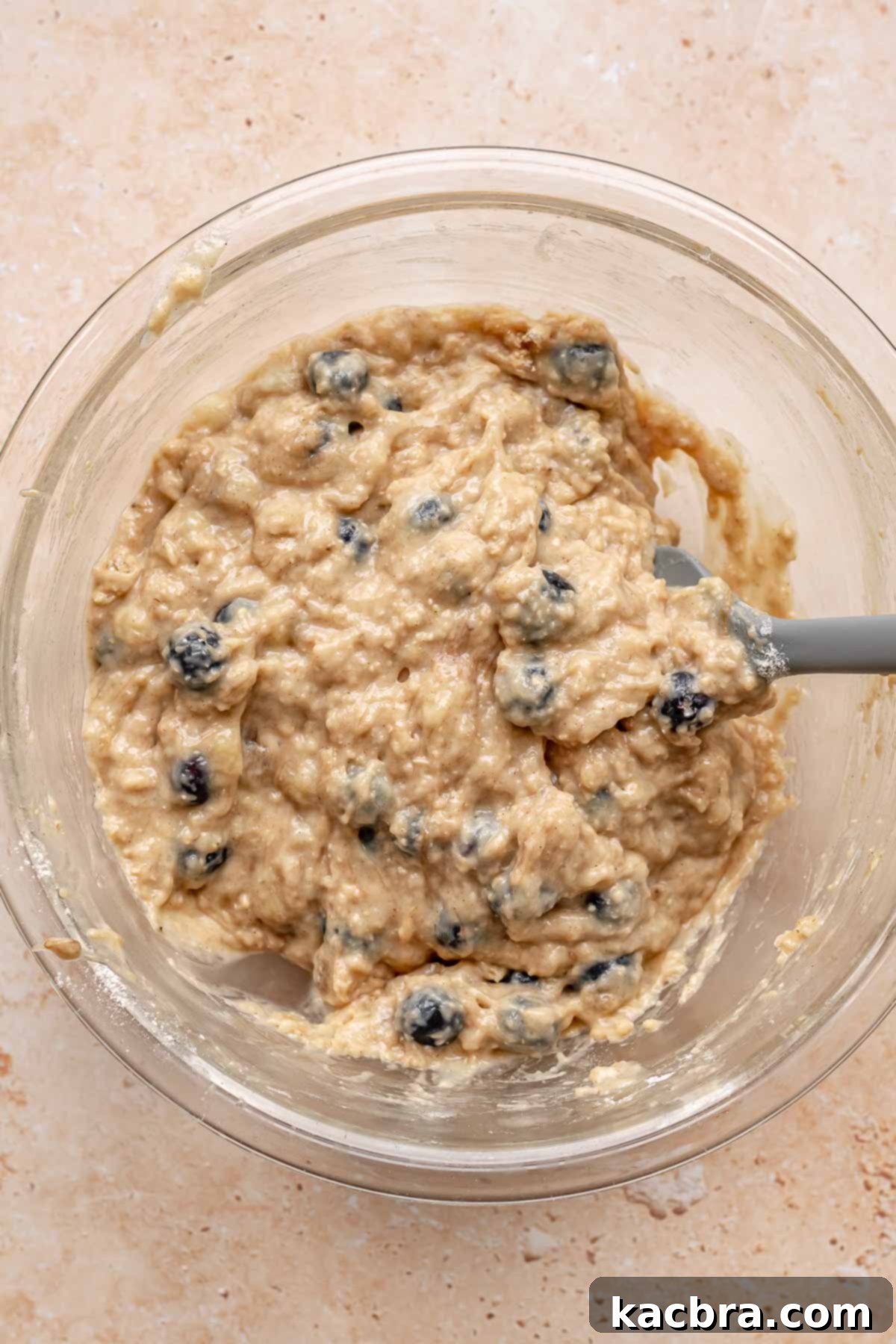 Sweet and Healthy Banana Blueberry Oatmeal Muffins 12 A spatula folding flour-coated blueberries into muffin batter.