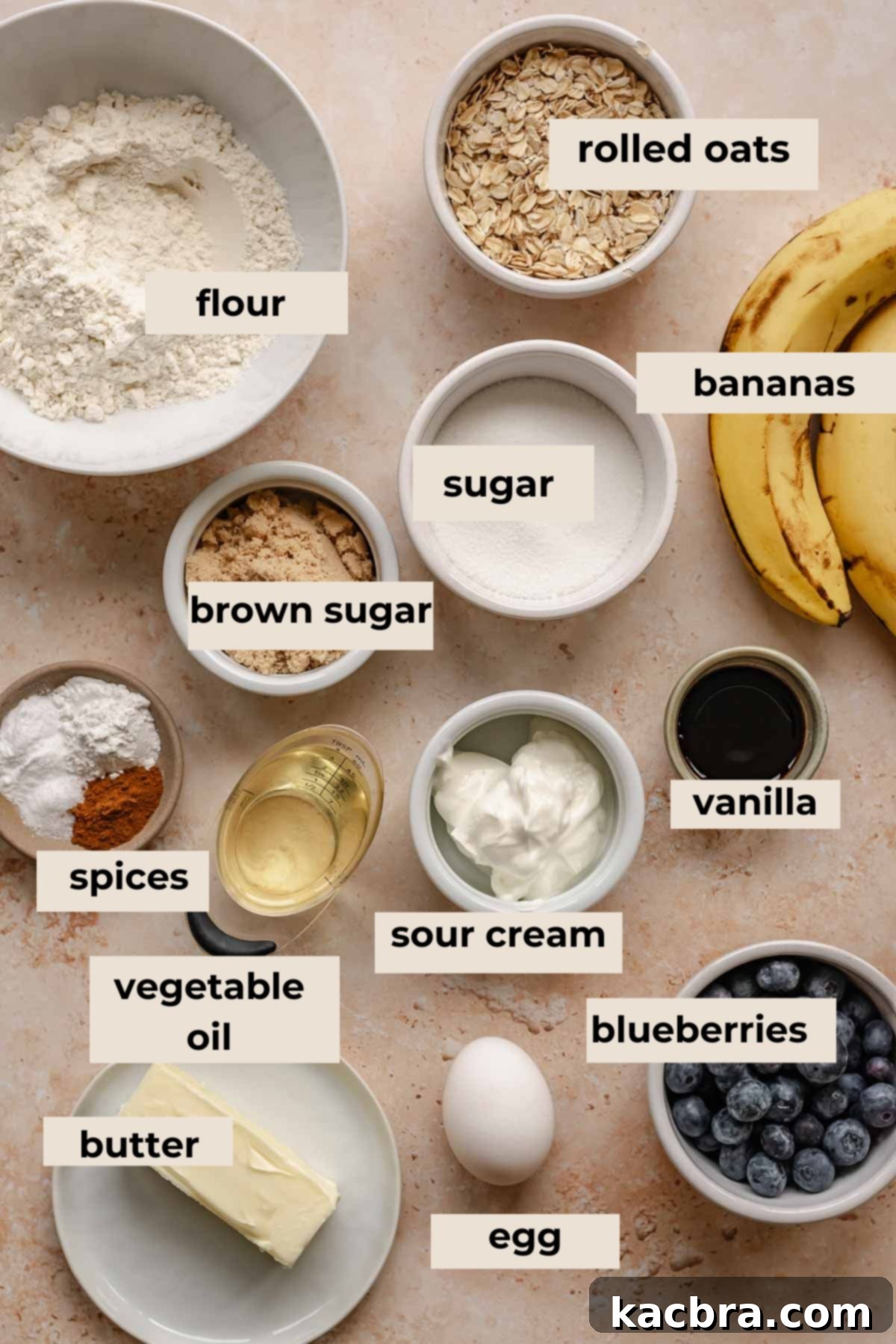 Sweet and Healthy Banana Blueberry Oatmeal Muffins 3 A collection of ingredients for banana blueberry oatmeal muffins, including oats, bananas, blueberries, flour, butter, oil, and sour cream.