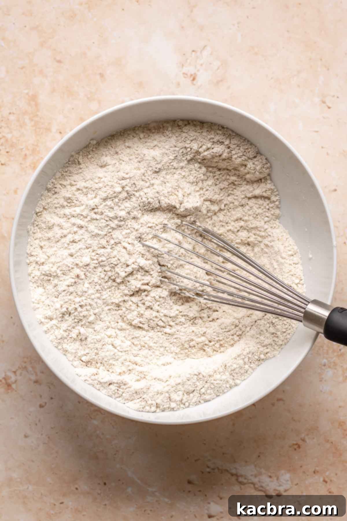 Sweet and Healthy Banana Blueberry Oatmeal Muffins 6 Dry ingredients in a mixing bowl with a whisk.