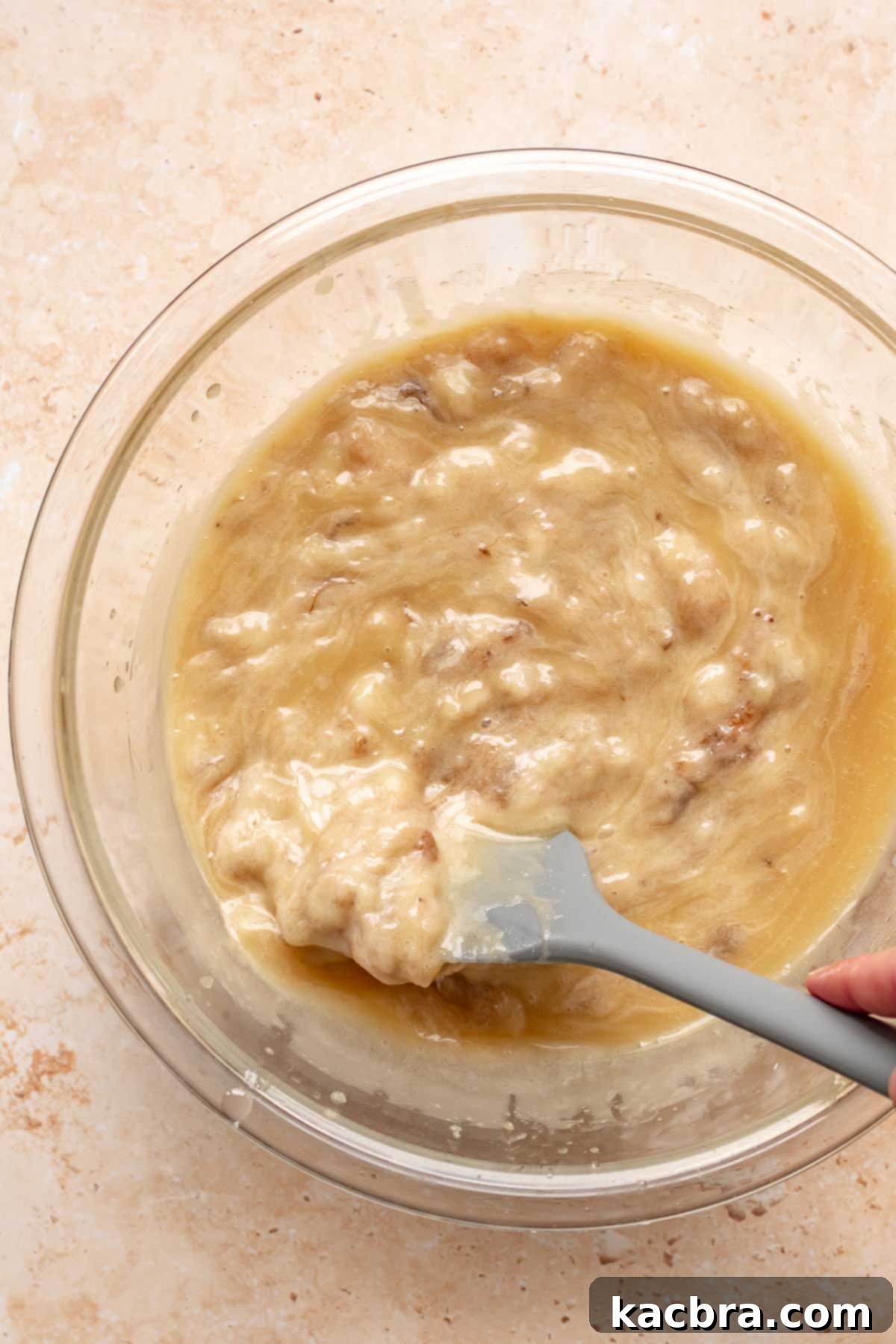 Sweet and Healthy Banana Blueberry Oatmeal Muffins 8 A rubber spatula gently folding mashed bananas into muffin batter.