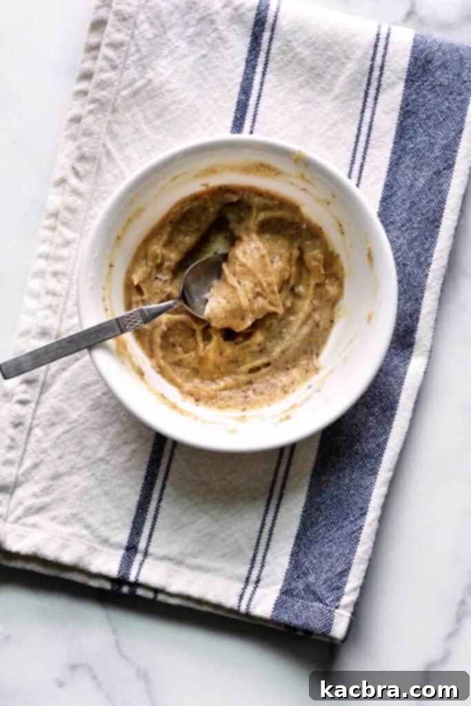 Overhead shot of a bowl of soft brown butter with a spoon in it. 