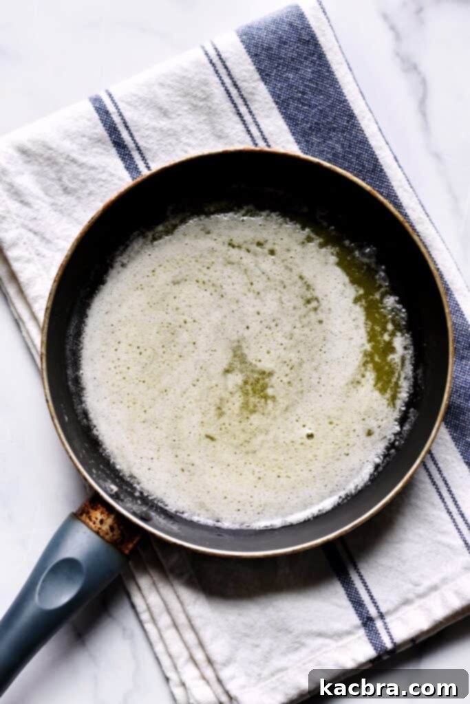 Overhead shot of melted butter in a pan that has started foaming on the top.