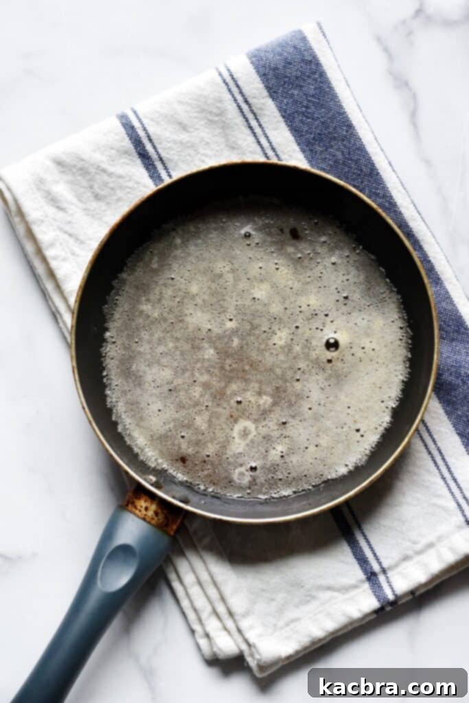 Over head shot of butter in a pan that has changed to a brown color and is only slightly foamy on top.