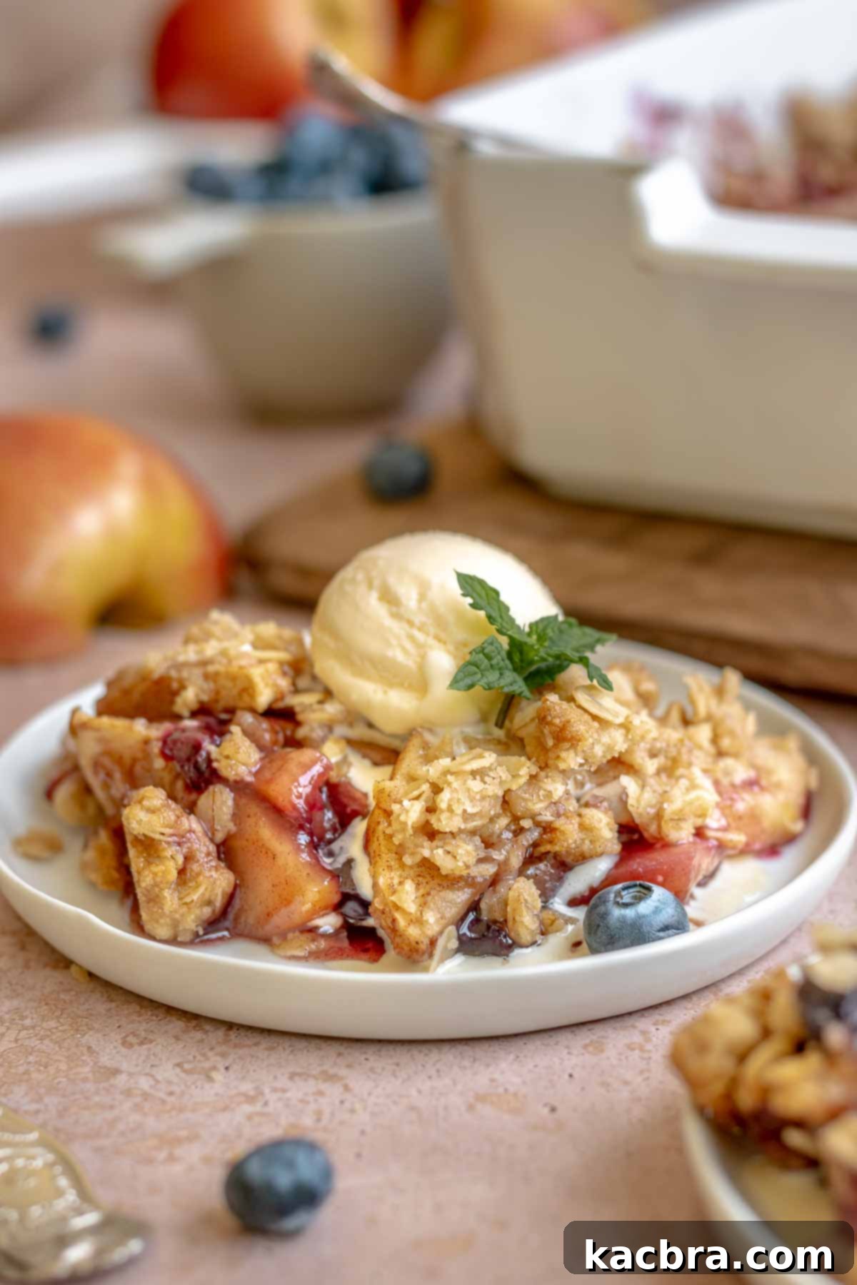 A serving of apple blueberry crisp on a plate with a melting scoop of vanilla ice cream.
