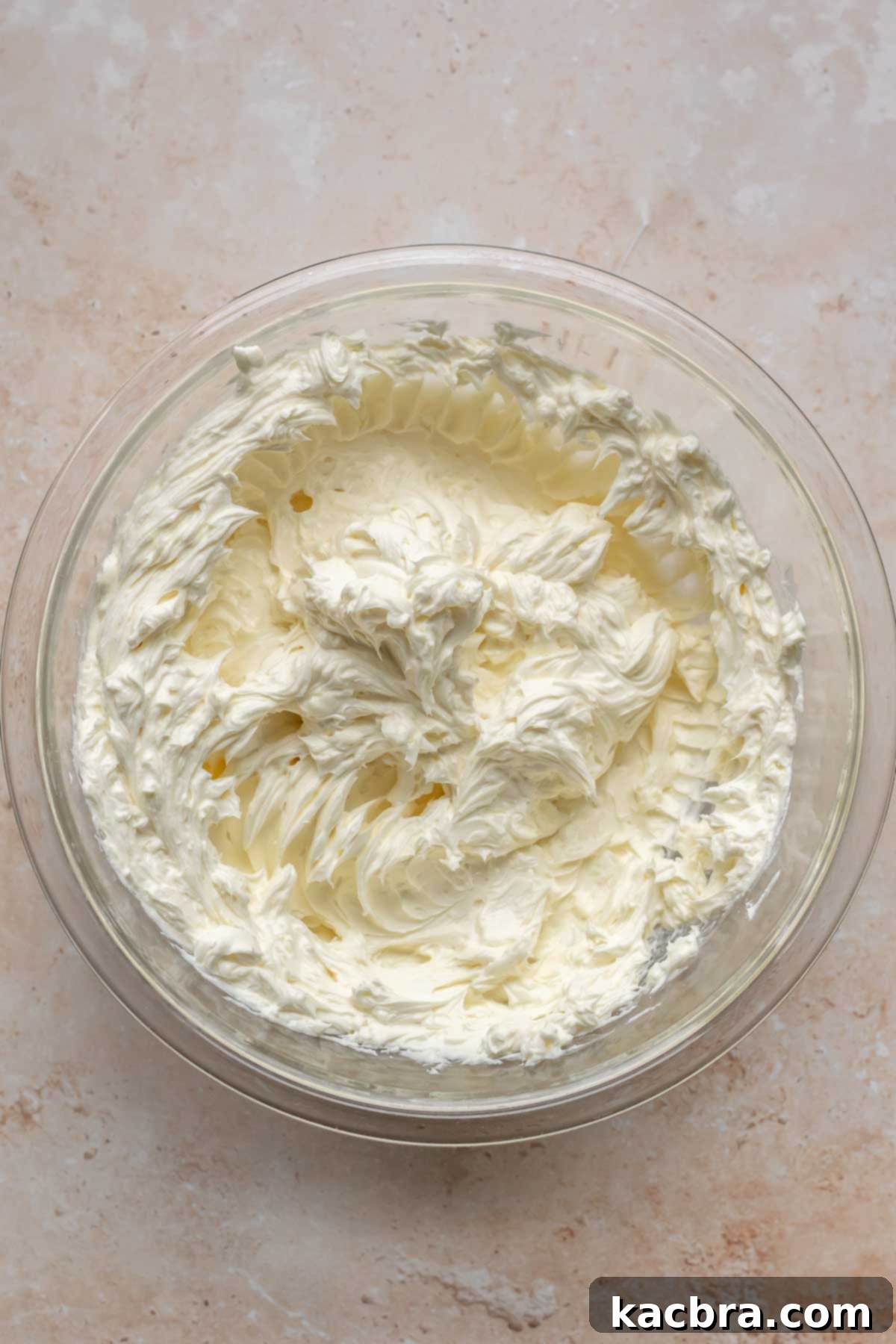 Cream cheese whisked in a mixing bowl.