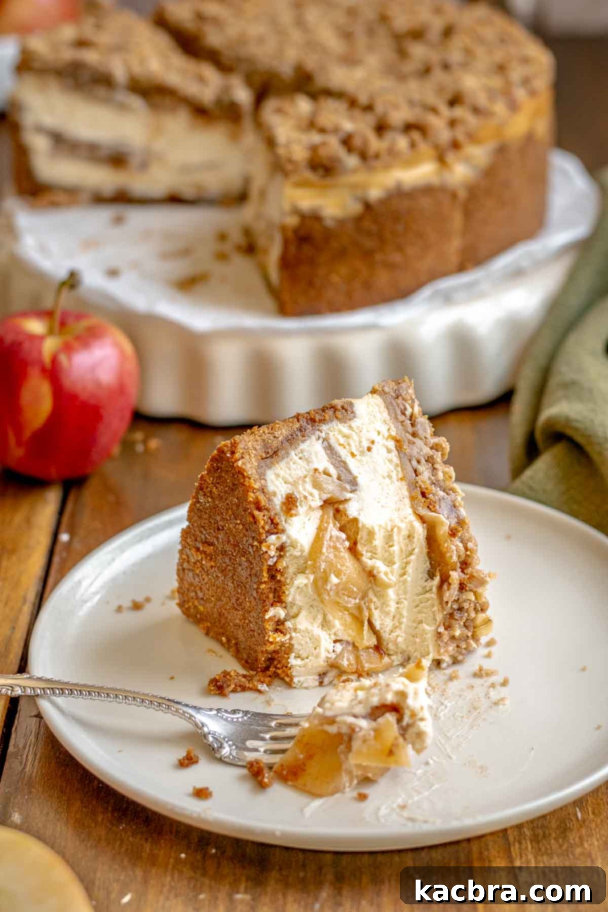 A piece of apple crisp cheesecake on a plate with bites removed.