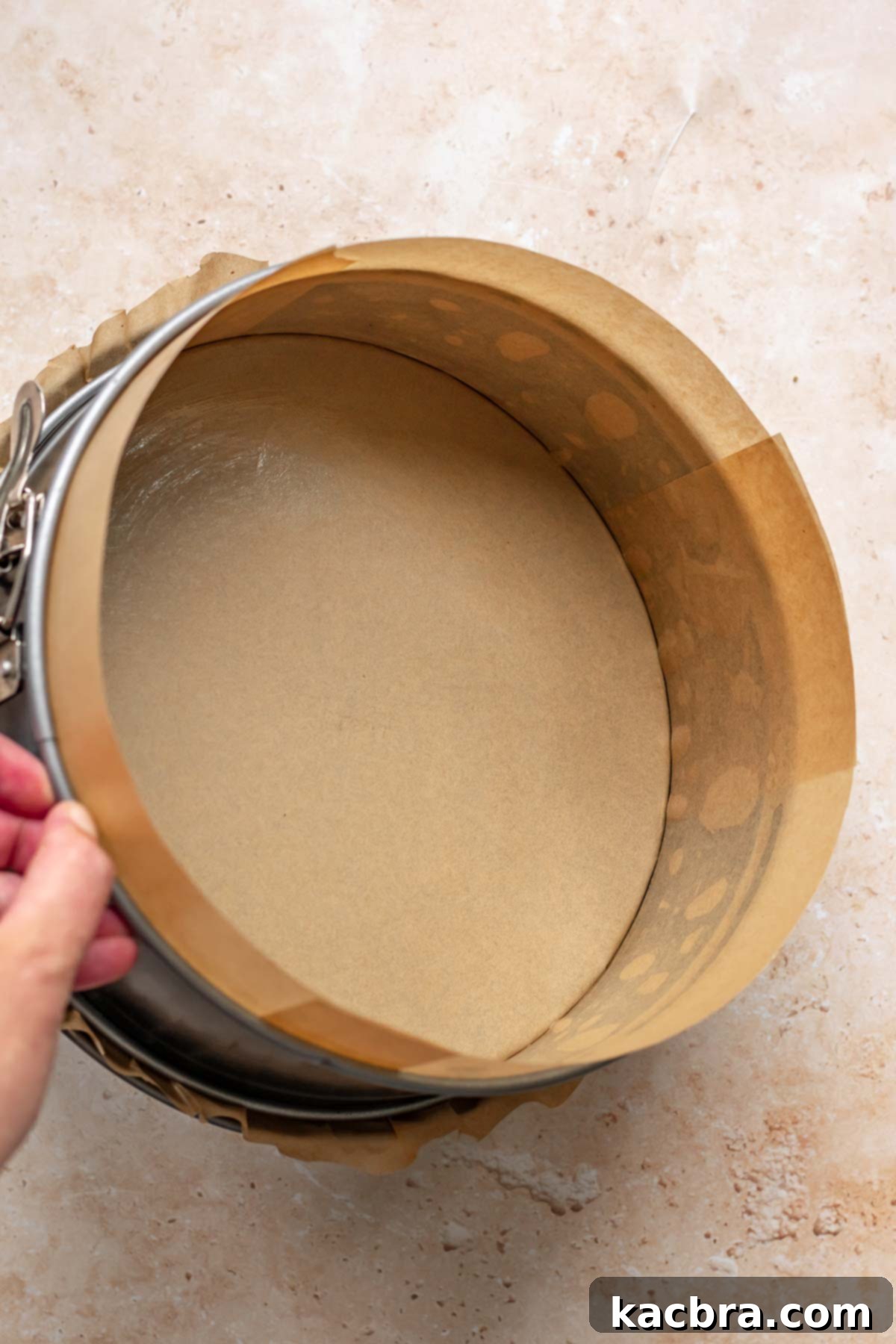 A springform pan fully lined with parchment paper.