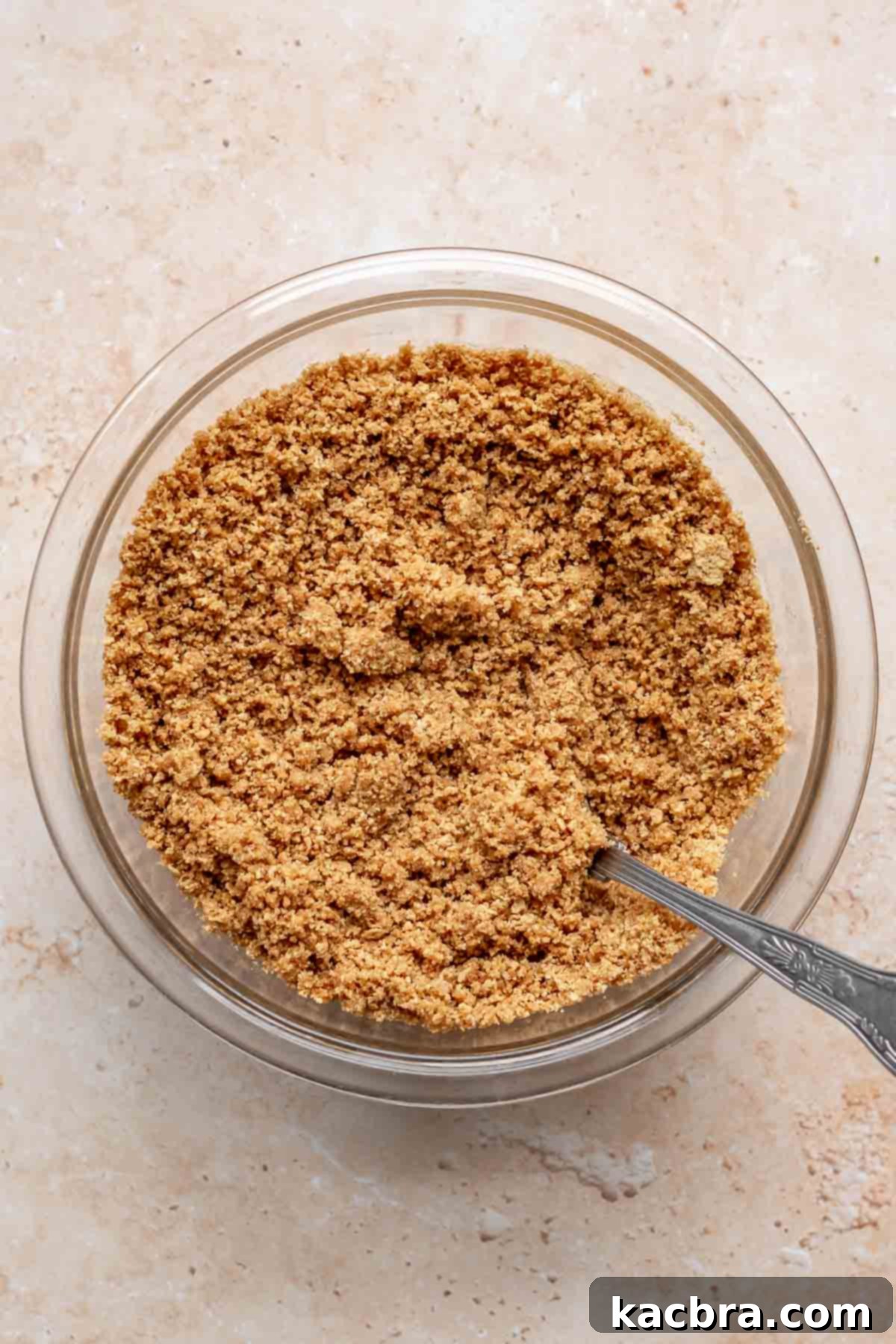 Graham cracker crumbs mixed in a bowl with a fork.