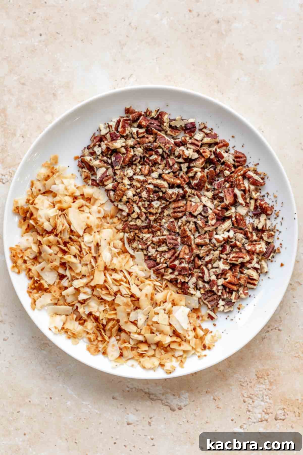 A bowl filled with freshly toasted pecan pieces and coconut flakes, ready to be added to the cookie dough.