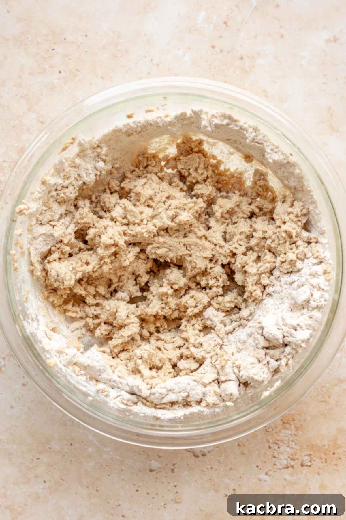 Cookie dough in a bowl with flour partially mixed in, indicating the stage before full incorporation of dry ingredients.