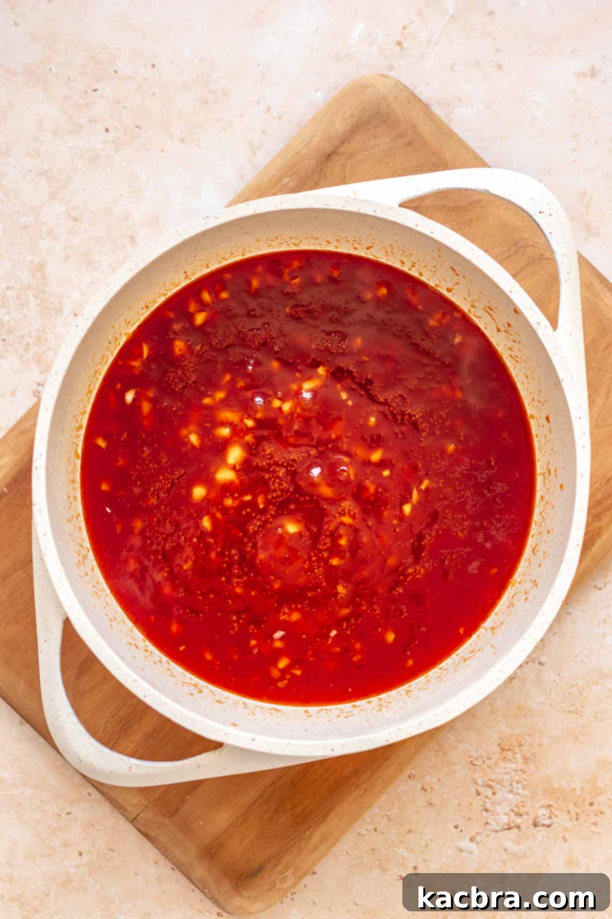 Ingredients for honey sriracha sauce mixed together in a saucepan.