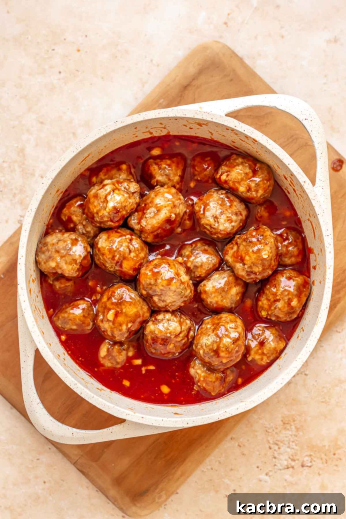 Cooked meatballs in honey sriracha sauce in a saucepan.