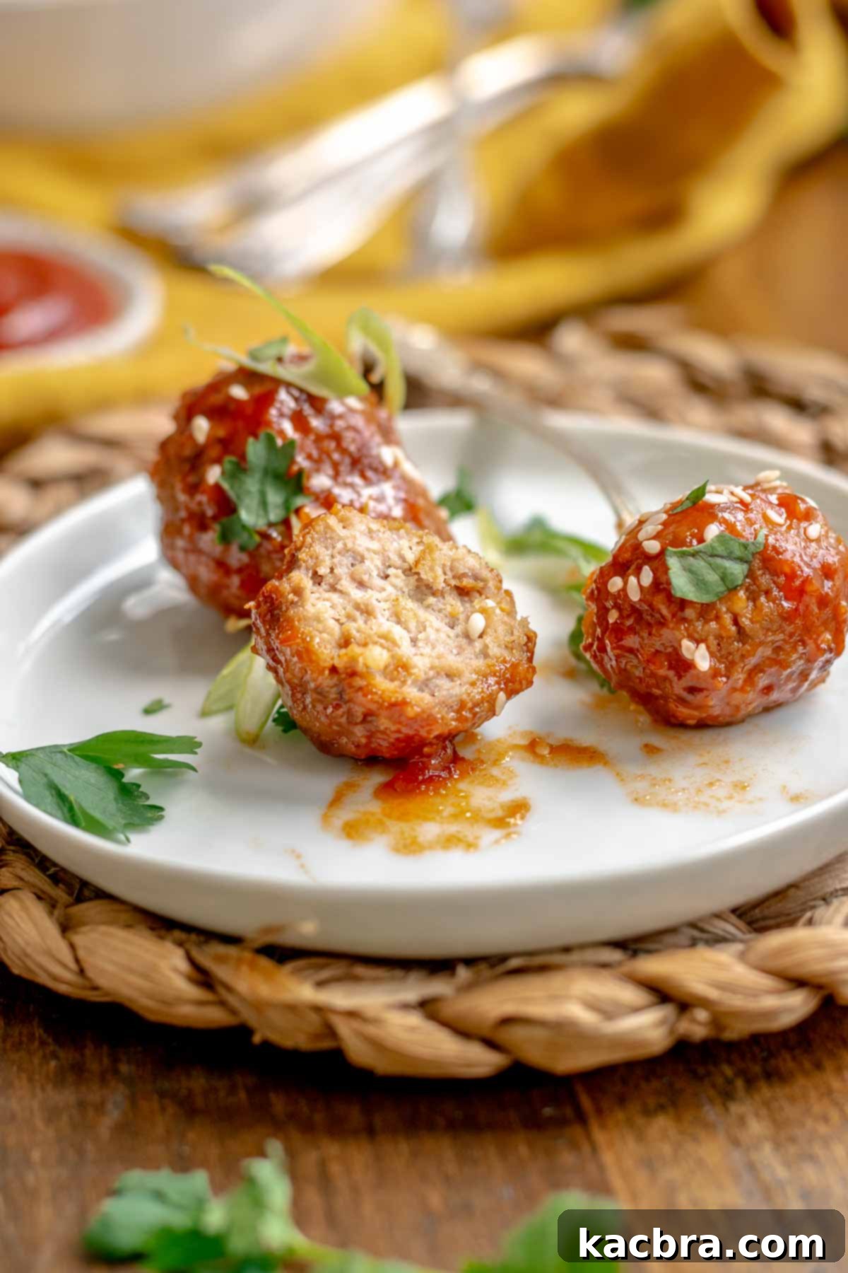 Honey sriracha meatballs on a plate. One is broken open to show the center.
