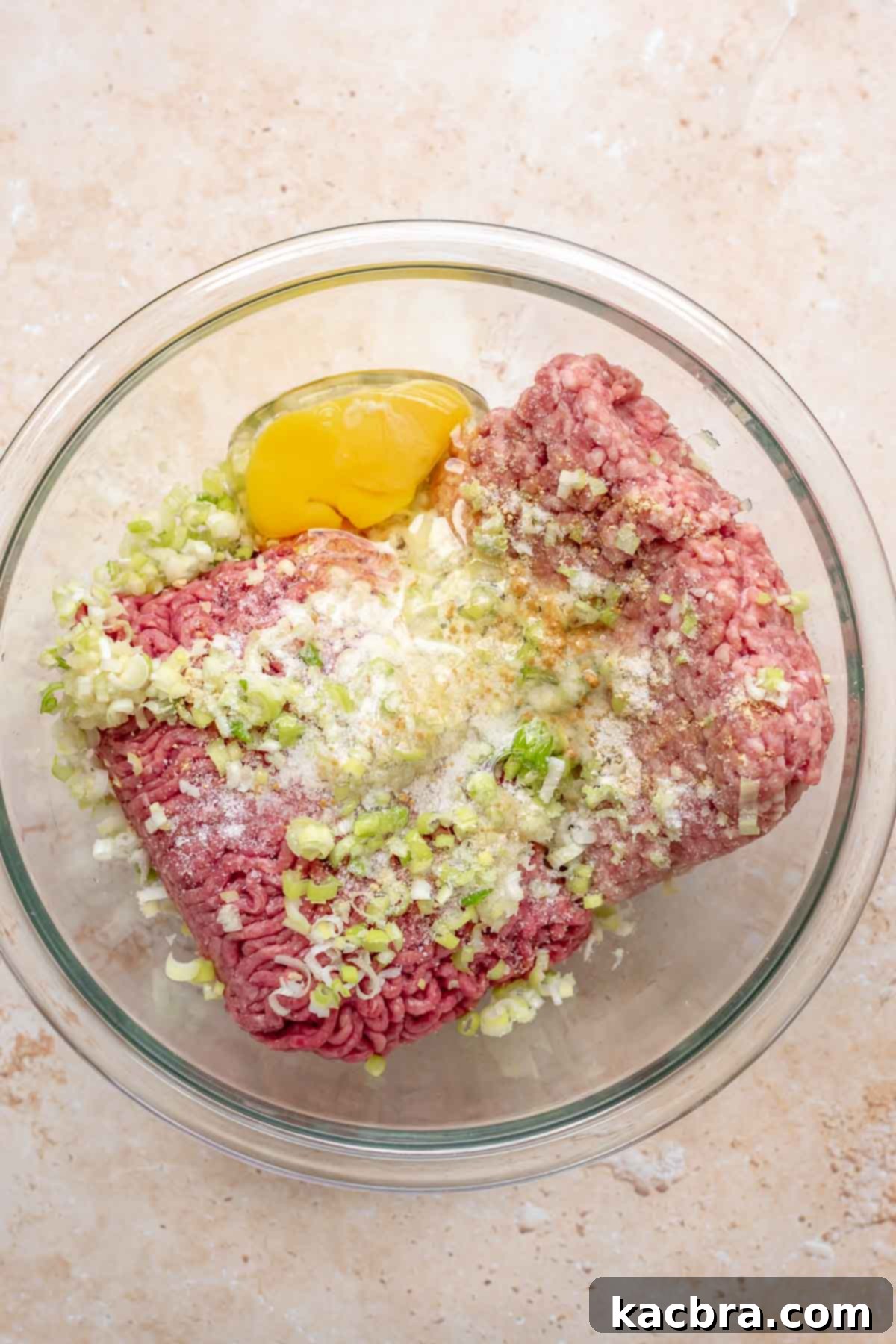 Ground meats and meatball ingredients in a bowl before mixing.
