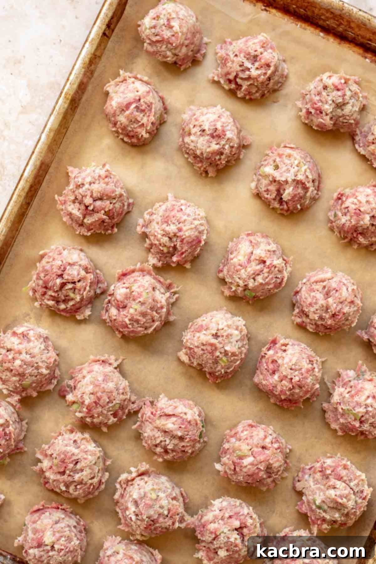 Scoops of meatballs on a prepared pan.