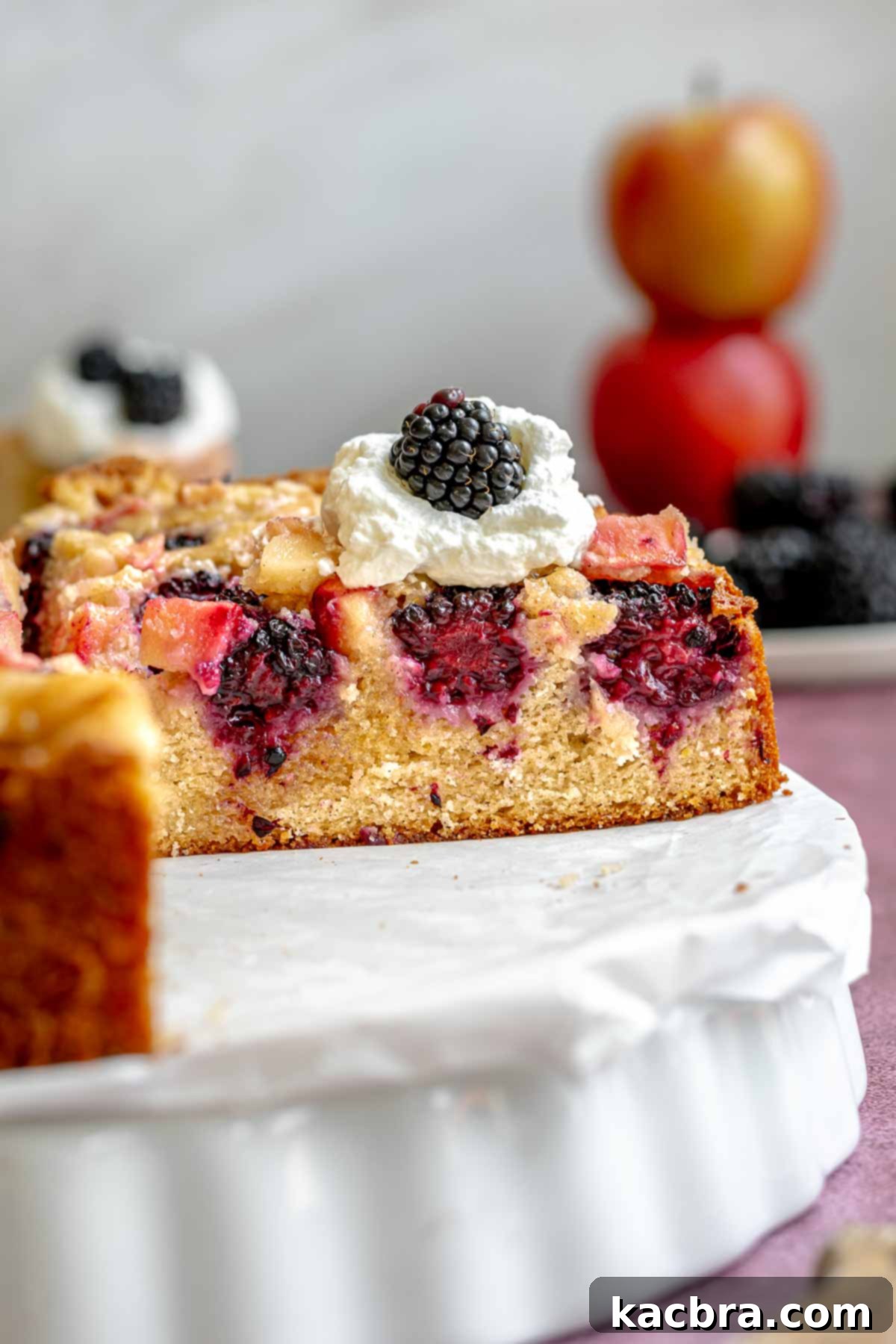 A beautifully sliced apple and blackberry cake, revealing its tender crumb and layers of fruit.
